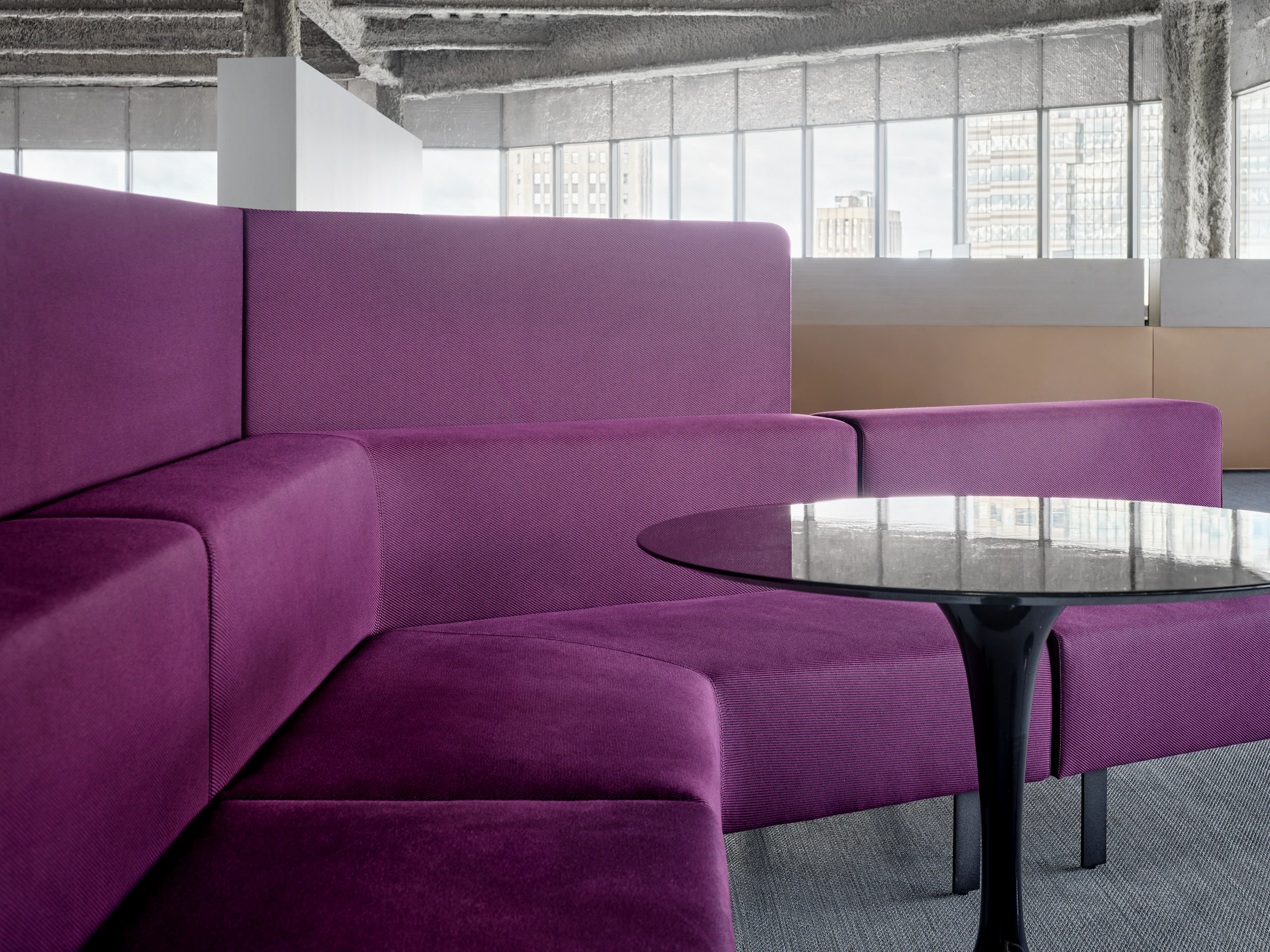 A bench style lounge seating area is set up with a small round table sitting in front of the bench seating. There are also privacy screens attached to the back of the lounge seating.
