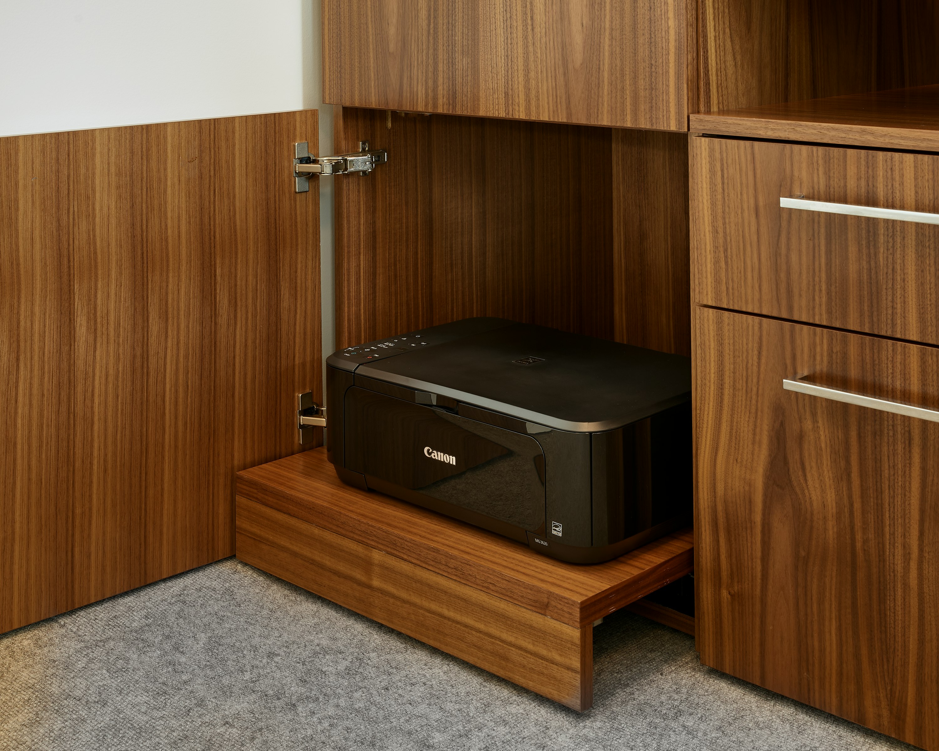 Detail view of a Geiger One Casegoods Private Office open printer storage drawer in Natural Flat Cut Walnut, viewed at an angle in a private office setting.