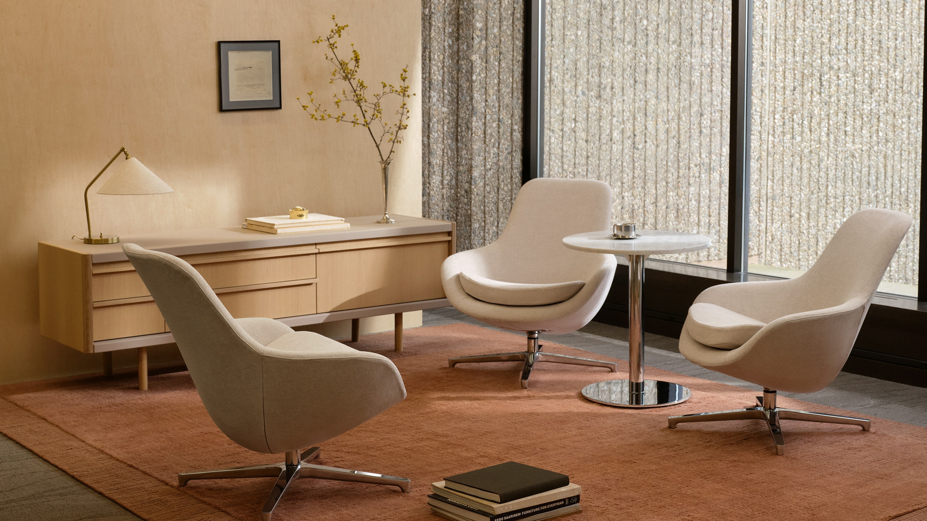 Three Saiba Lounge Chairs upholstered in Vionette in Desert Mix with polished aluminum bases positioned at varying angles, shown with an NL Side Table and a New Canaan Media Unit in a lounge setting.