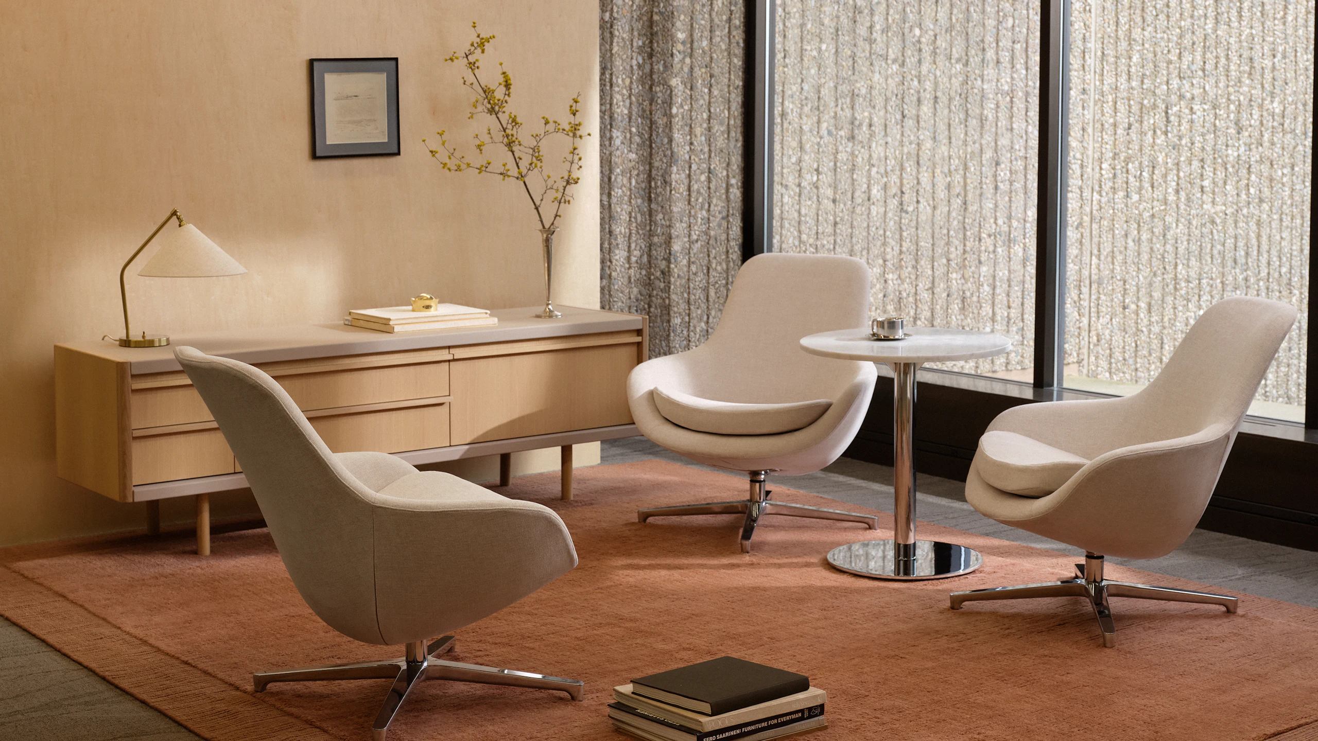 Three Saiba Lounge Chairs upholstered in Vionette in Desert Mix with polished aluminum bases positioned at varying angles, shown with an NL Side Table and a New Canaan Media Unit in a lounge setting.