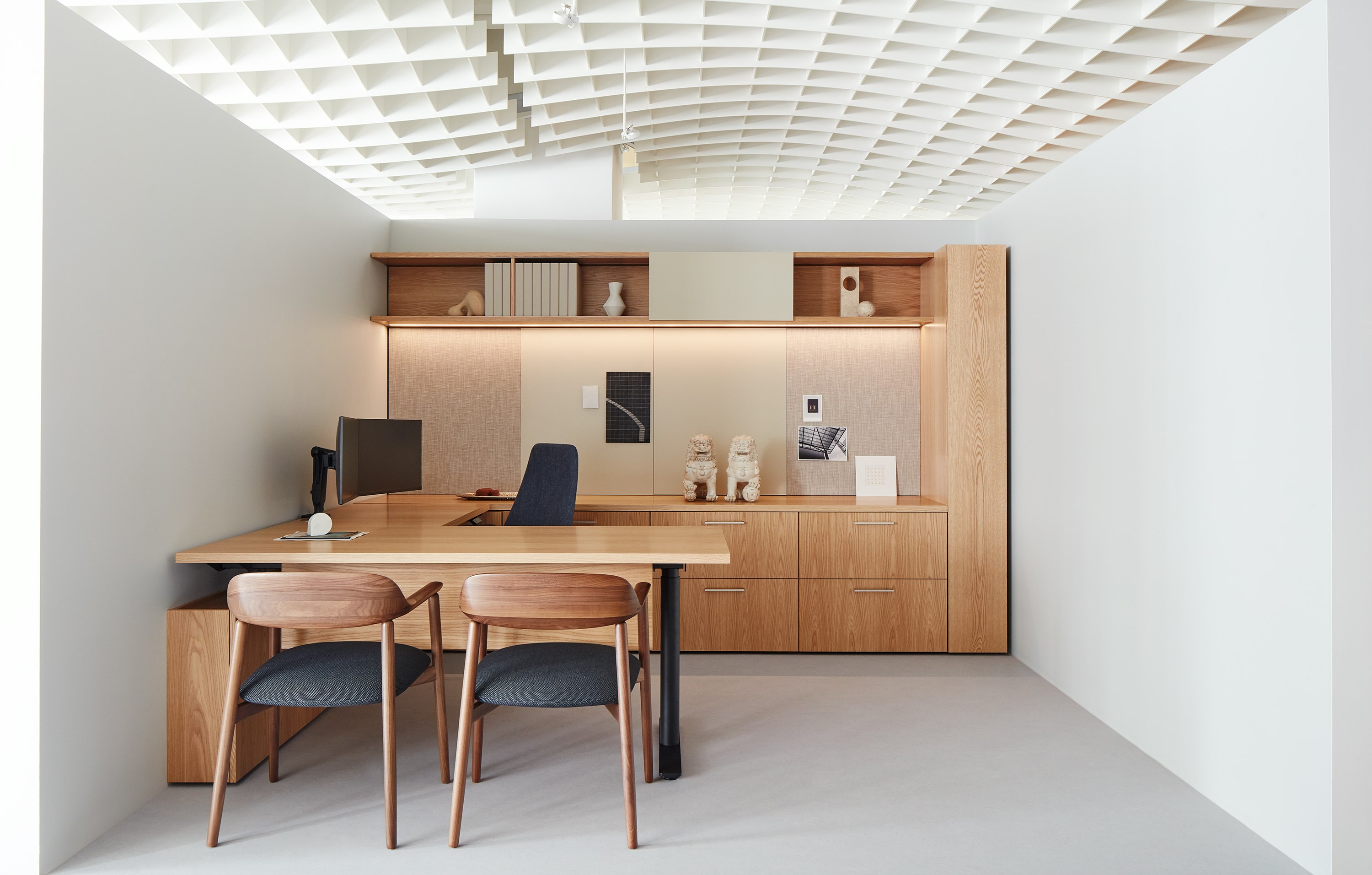 A private office vignette in the Geiger showroom, featuring Geiger One Casegoods with matte sand backpainted glass, a Taper Chair, and Crosshatch Side Chairs.