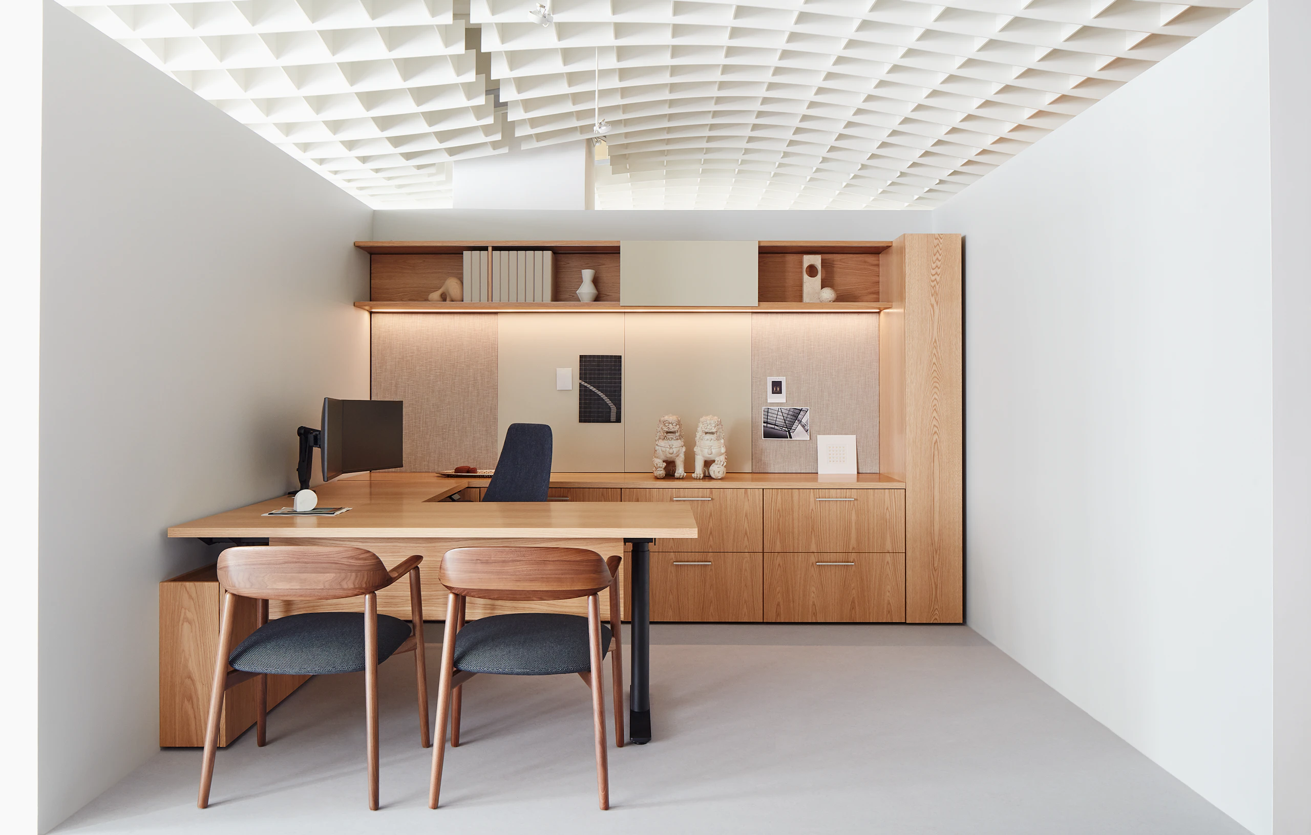 A private office vignette in the Geiger showroom, featuring Geiger One Casegoods with matte sand backpainted glass, a Taper Chair, and Crosshatch Side Chairs.