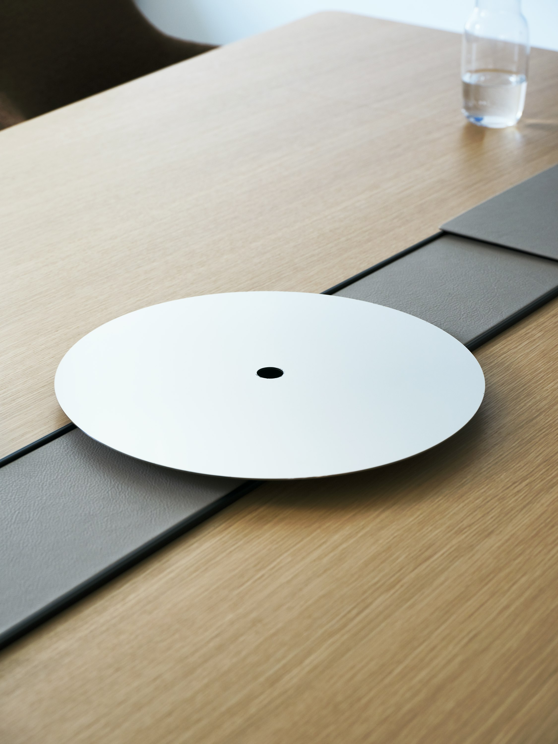 Detail view of the Ascent Conference Table designed by EOOS, shown in Natural Rift Cut Oak with the power trough covered in Prone leather in Lute and an AV platform.