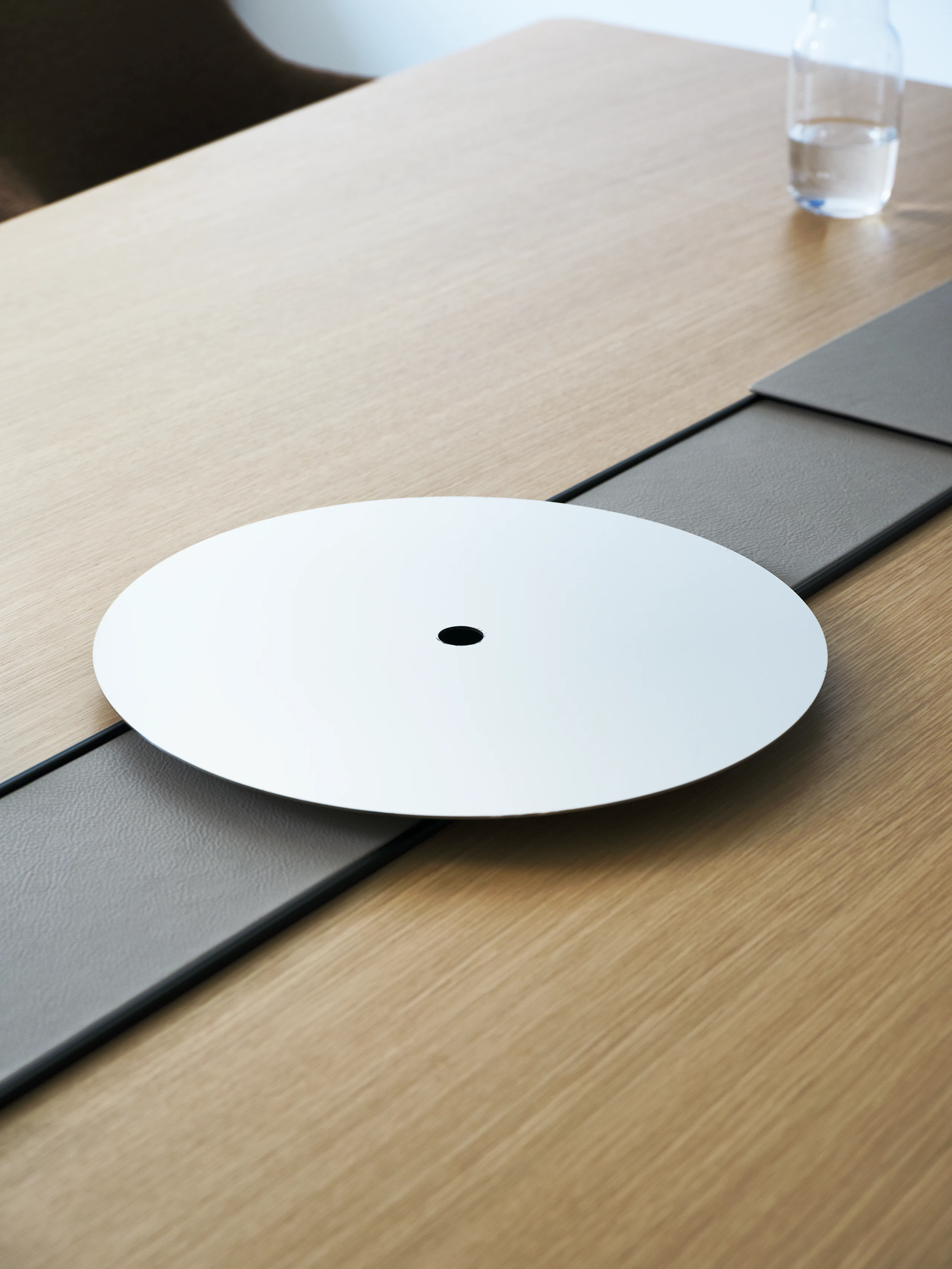 Detail view of the Ascent Conference Table, designed by EOOS, shown in Natural Rift Cut Oak with the power trough covered in Prone leather in Lute and an AV platform.
