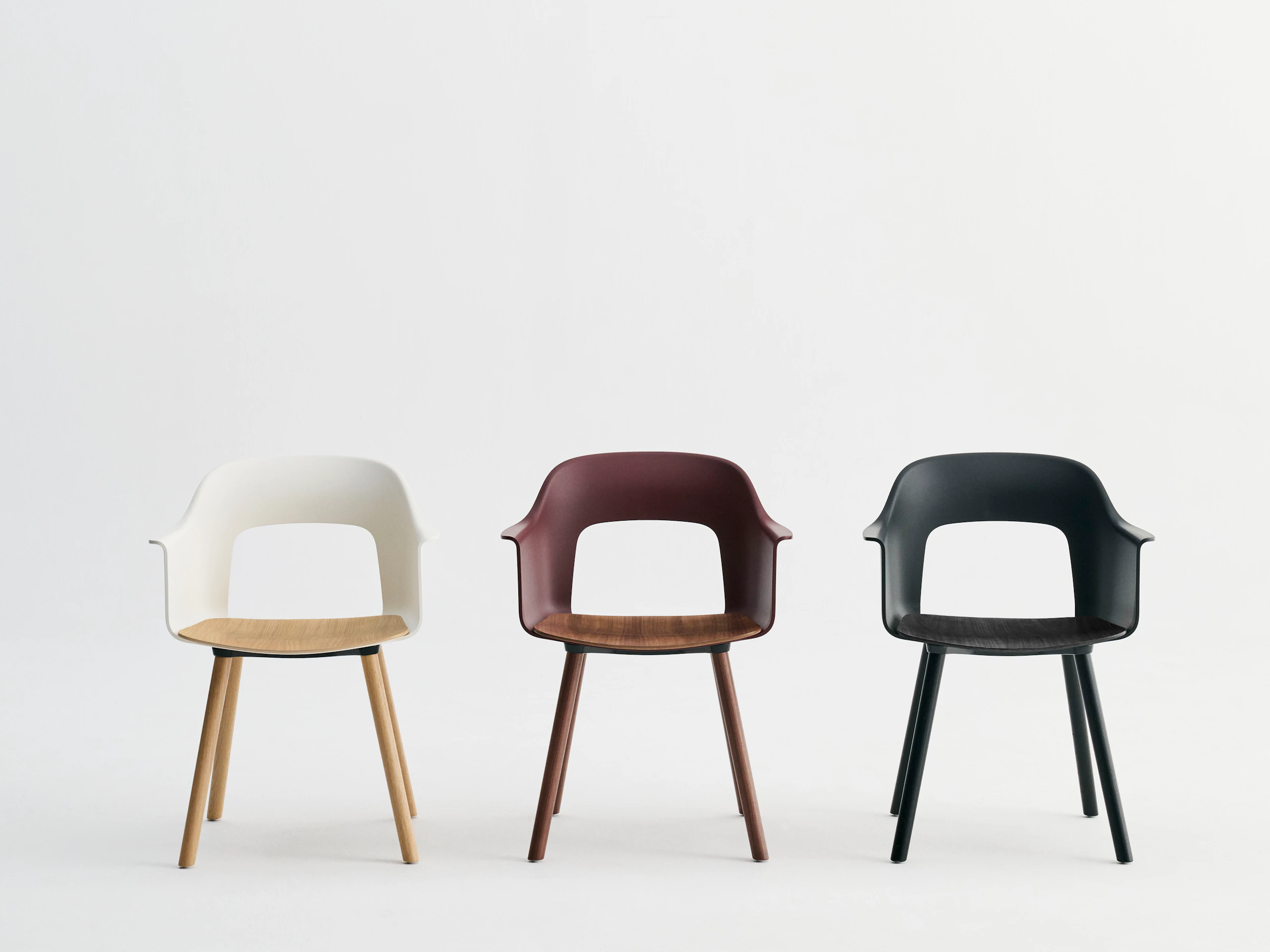 Lineup of Layout Armchairs 222 in wood base with shells in cream, Bordeaux, black, and wood-finish seats.