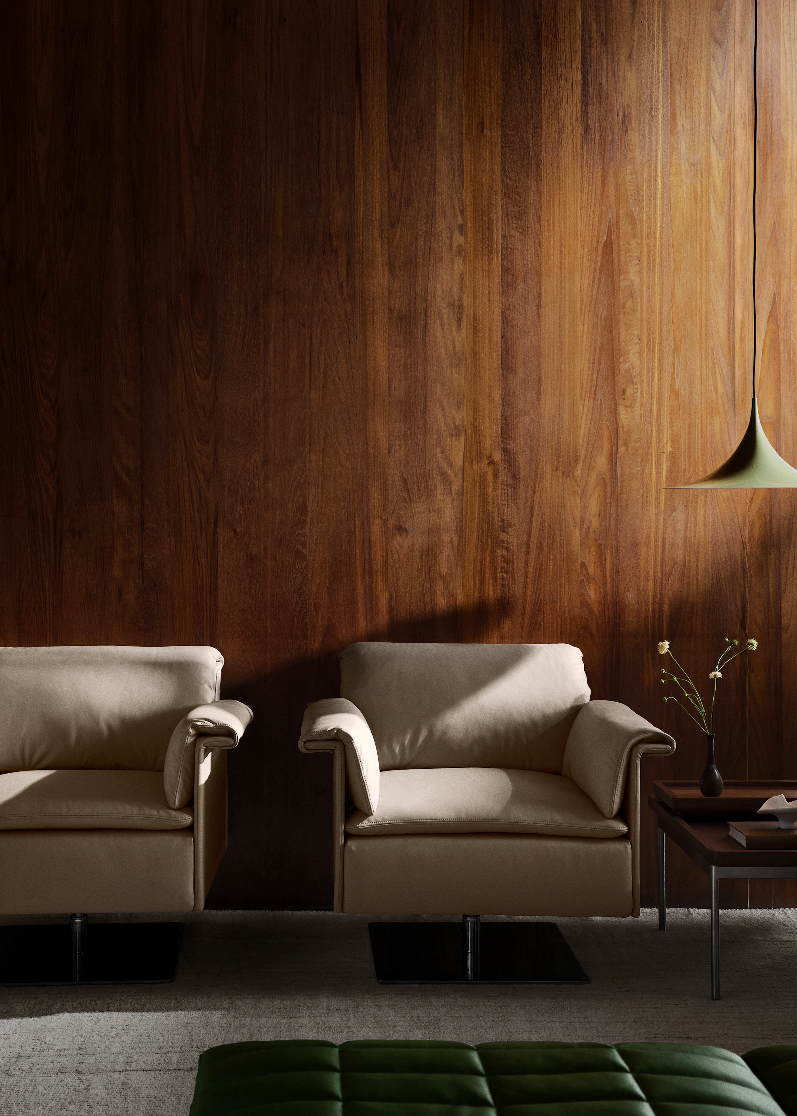 Two Mantle Club Chairs designed by BassamFellows for Geiger, upholstered in light leather with satin chrome swivel bases, paired with a Tuxedo Component Side Table in a lounge setting.