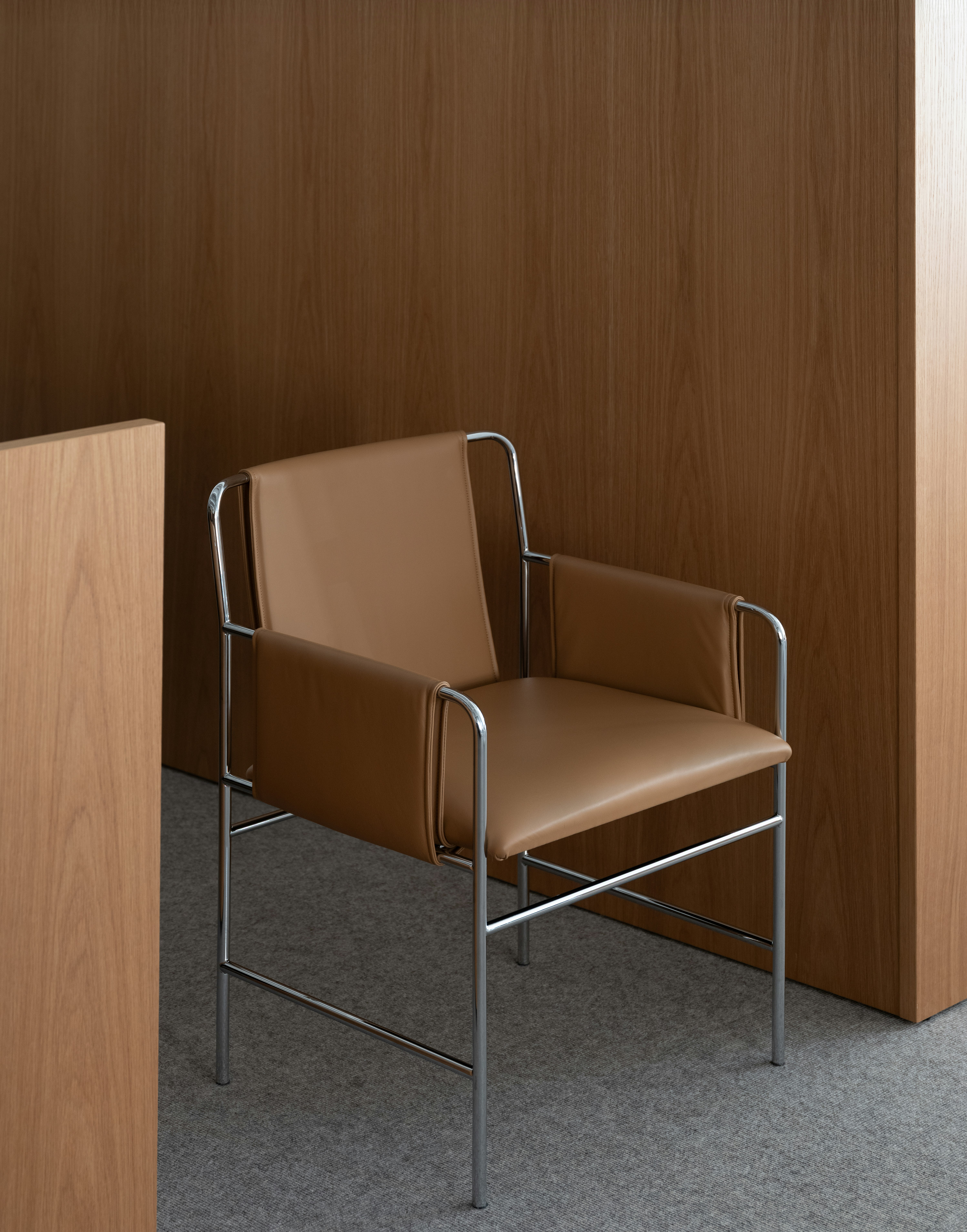 Envelope Chair upholstered with Bristol Leather in Camel with a Chrome Base beside viewed at an angle.