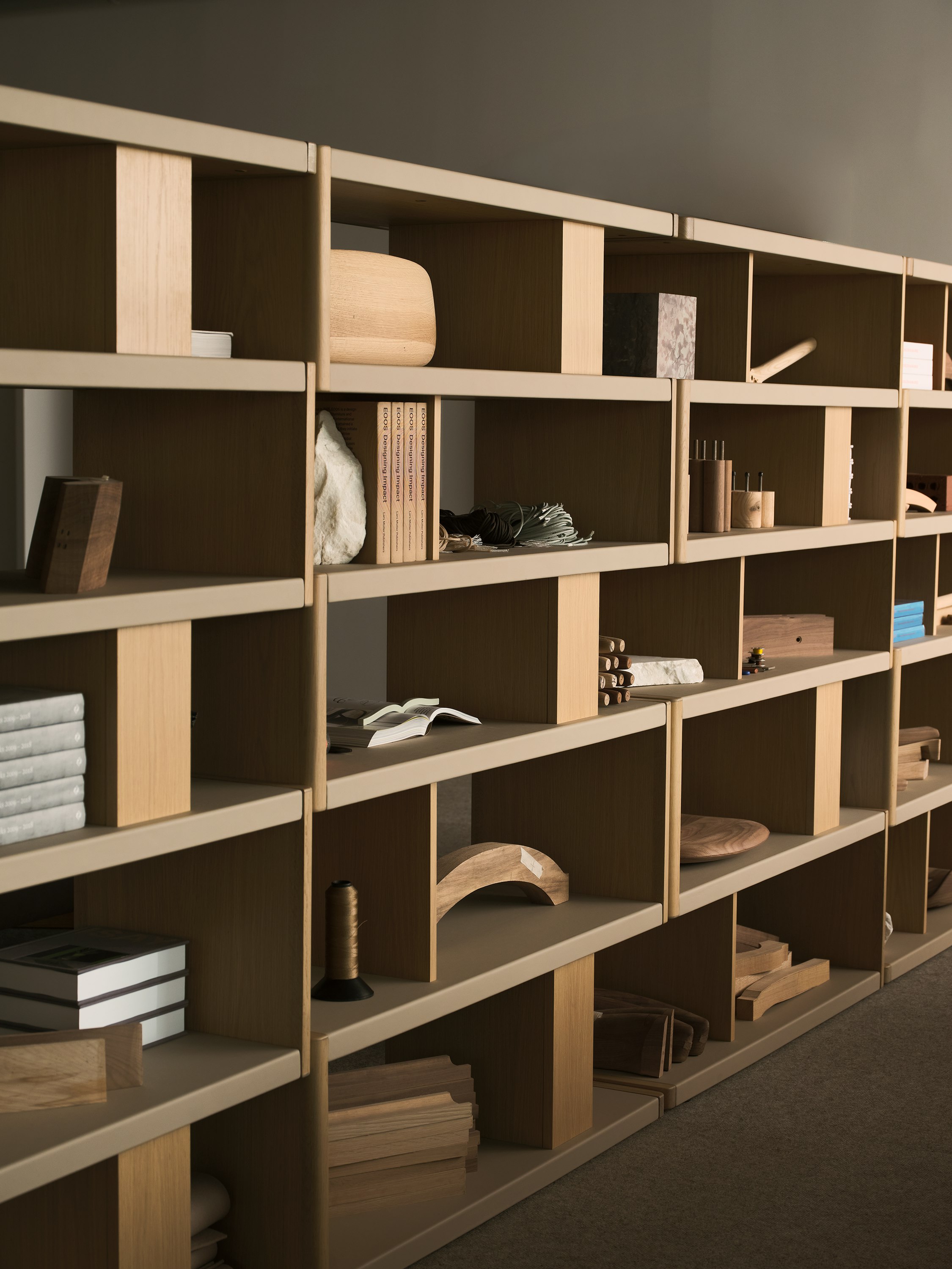 Various New Canaan Tall Bookshelves in Light Oak wrapped with Bristol Leather in Champagne arranged side by side and styled with various objects, viewed at an angle.