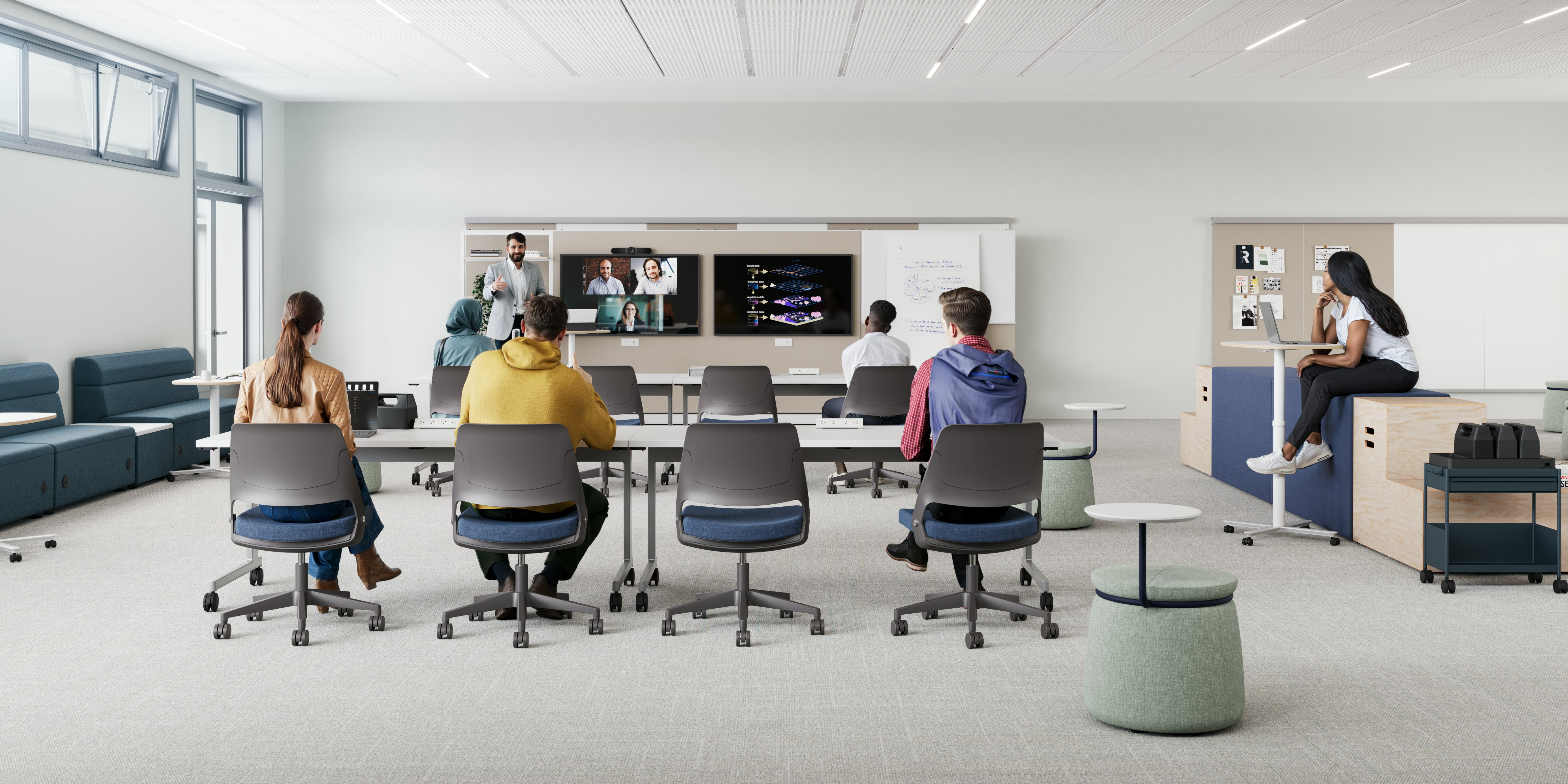 Modern classroom setting furnished with long white tables and blue and white Fuld Nesting chairs. Students sit while paying attention to a lecture.