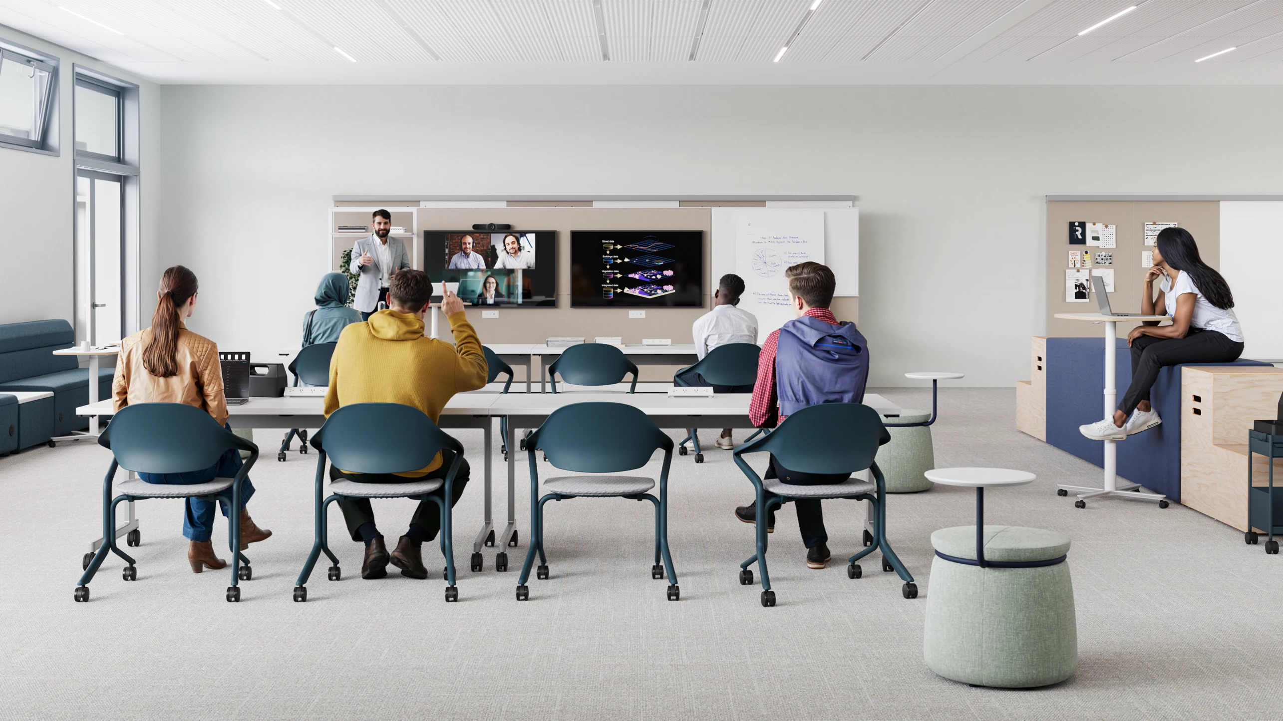 Modern classroom setting furnished with long white tables and blue and white Fuld Nesting chairs. Students sit while paying attention to a lecture.