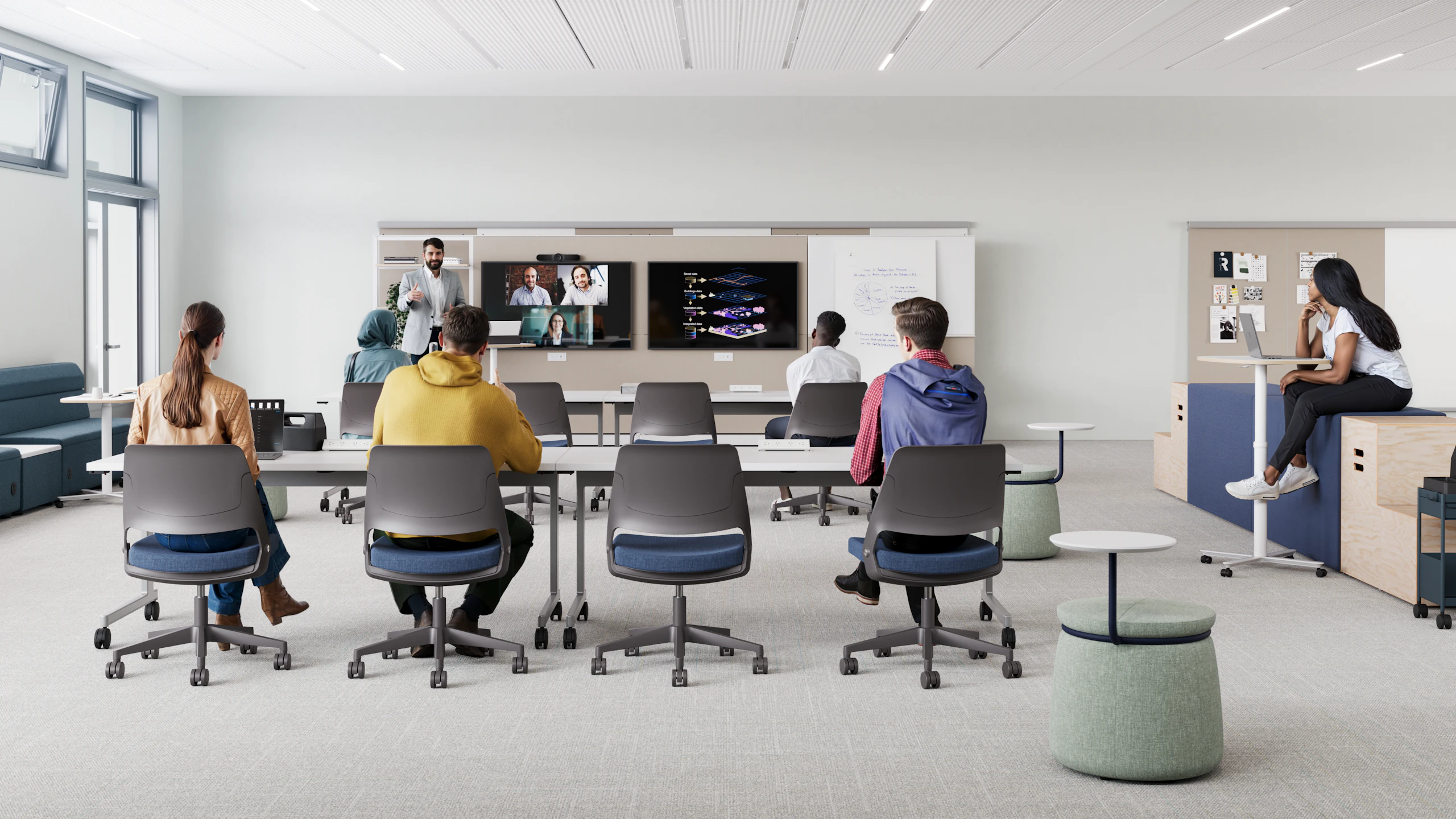 Modern classroom setting furnished with long white tables and blue and white Fuld Nesting chairs. Students sit while paying attention to a lecture.