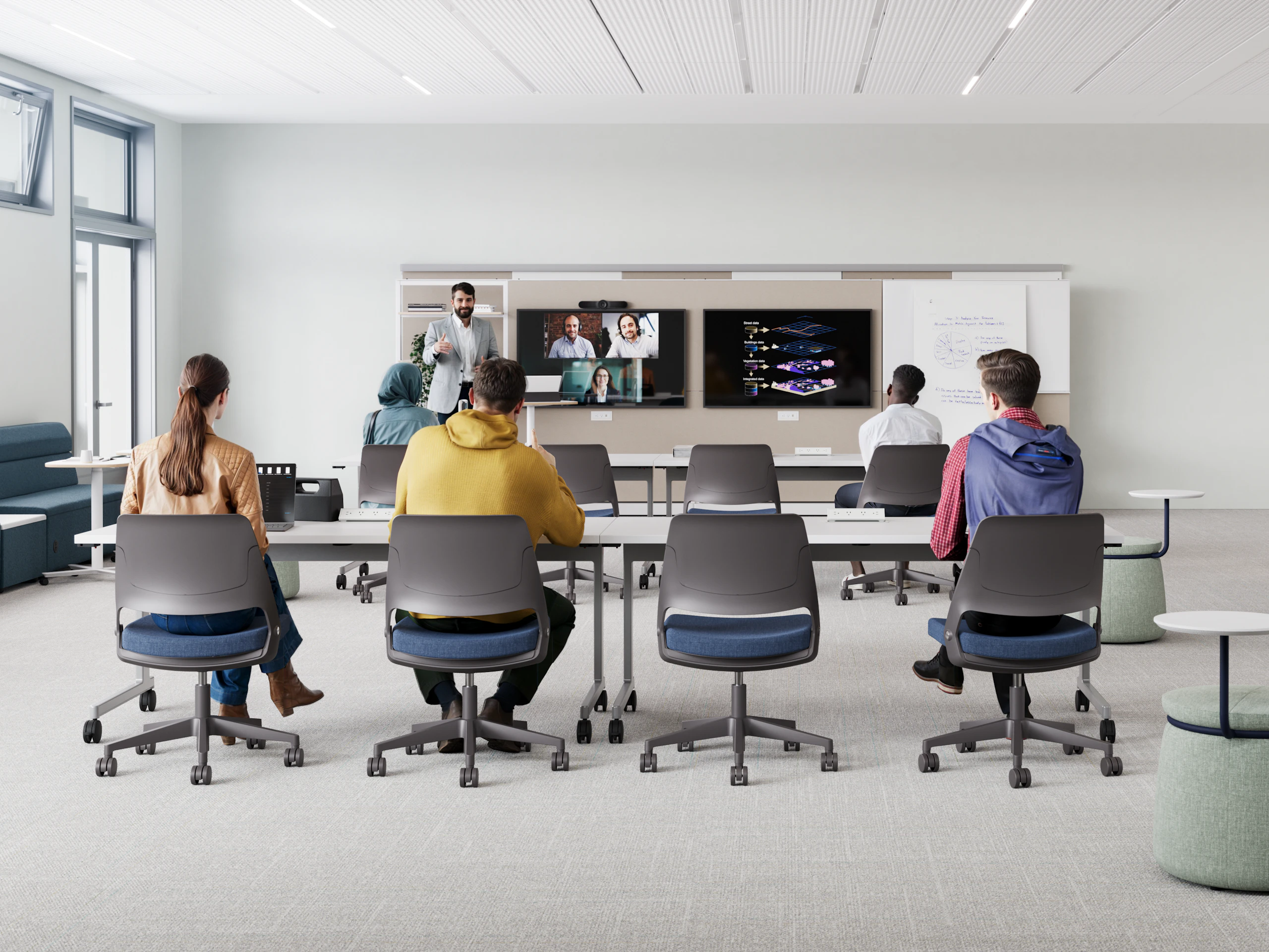 Modern classroom with focus on collaboration. Foreground features a long white table with laptops. Background shows enclosed booths with red fabric panels and white frames, some with seating and small tables inside.