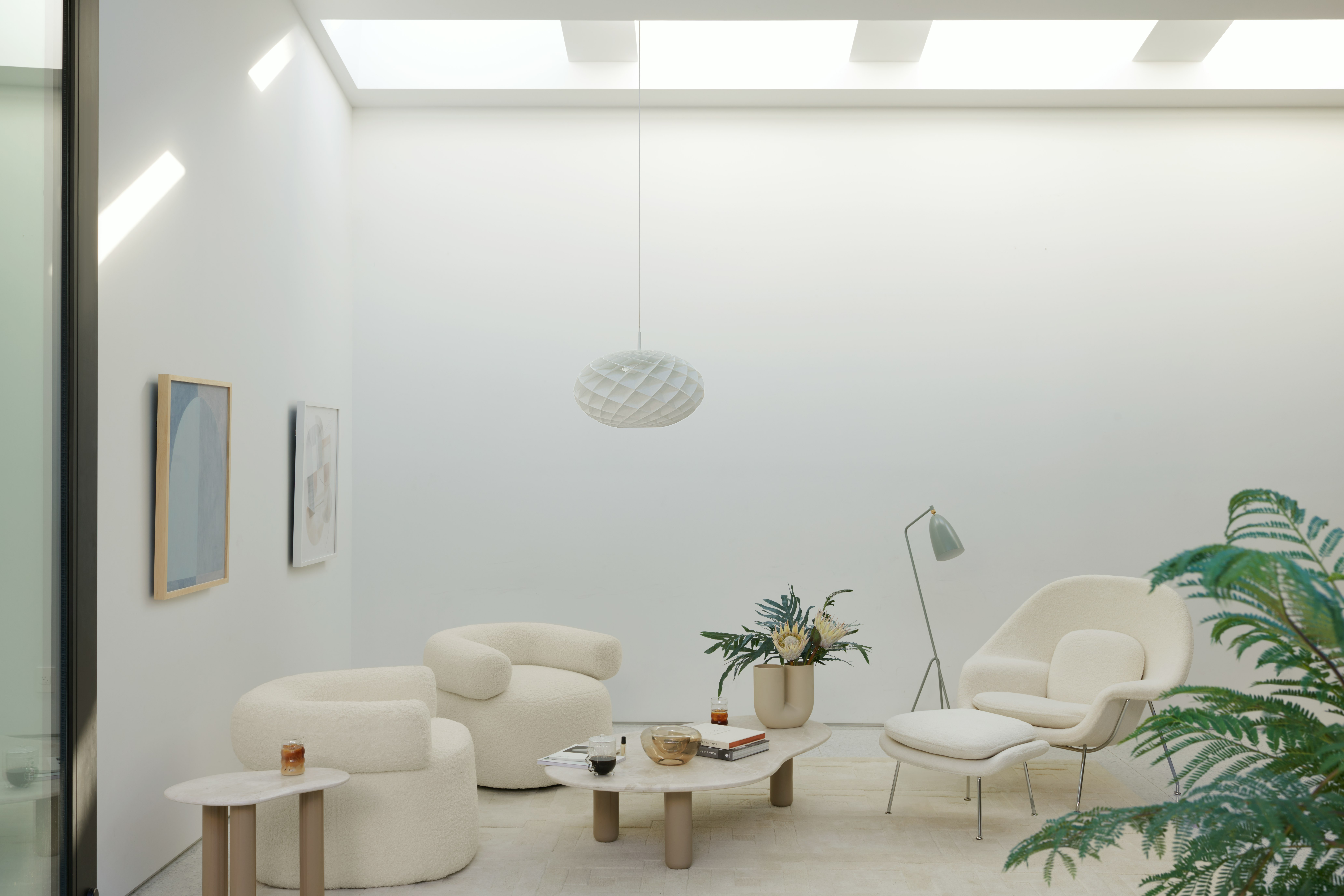 Seating area with Huggy chairs, Womb Chair, and Womb ottoman around a Piscina coffee table.
