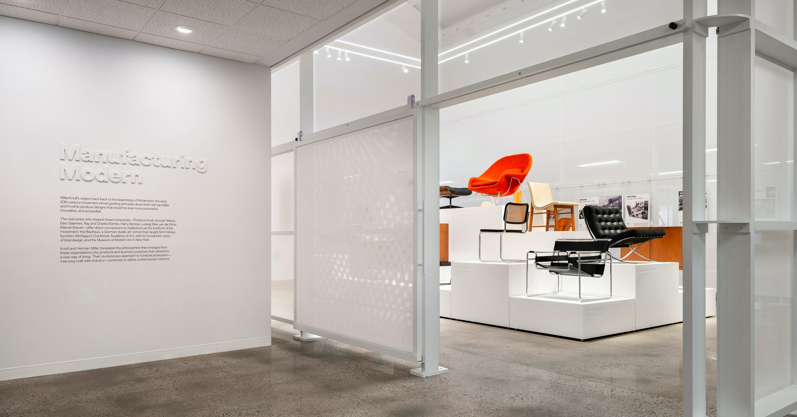 The entryway to the Manufacturing Modern exhibit at the MillerKnoll Archives with iconic furniture pieces, such as the Knoll Womb Chair and Barcelona Chair, on display in the background