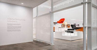 The entryway to the Manufacturing Modern exhibit at the MillerKnoll Archives with iconic furniture pieces, such as the Knoll Womb Chair and Barcelona Chair, on display in the background