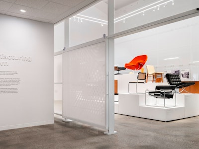 The entryway to the Manufacturing Modern exhibit at the MillerKnoll Archives with iconic furniture pieces, such as the Knoll Womb Chair and Barcelona Chair, on display in the background