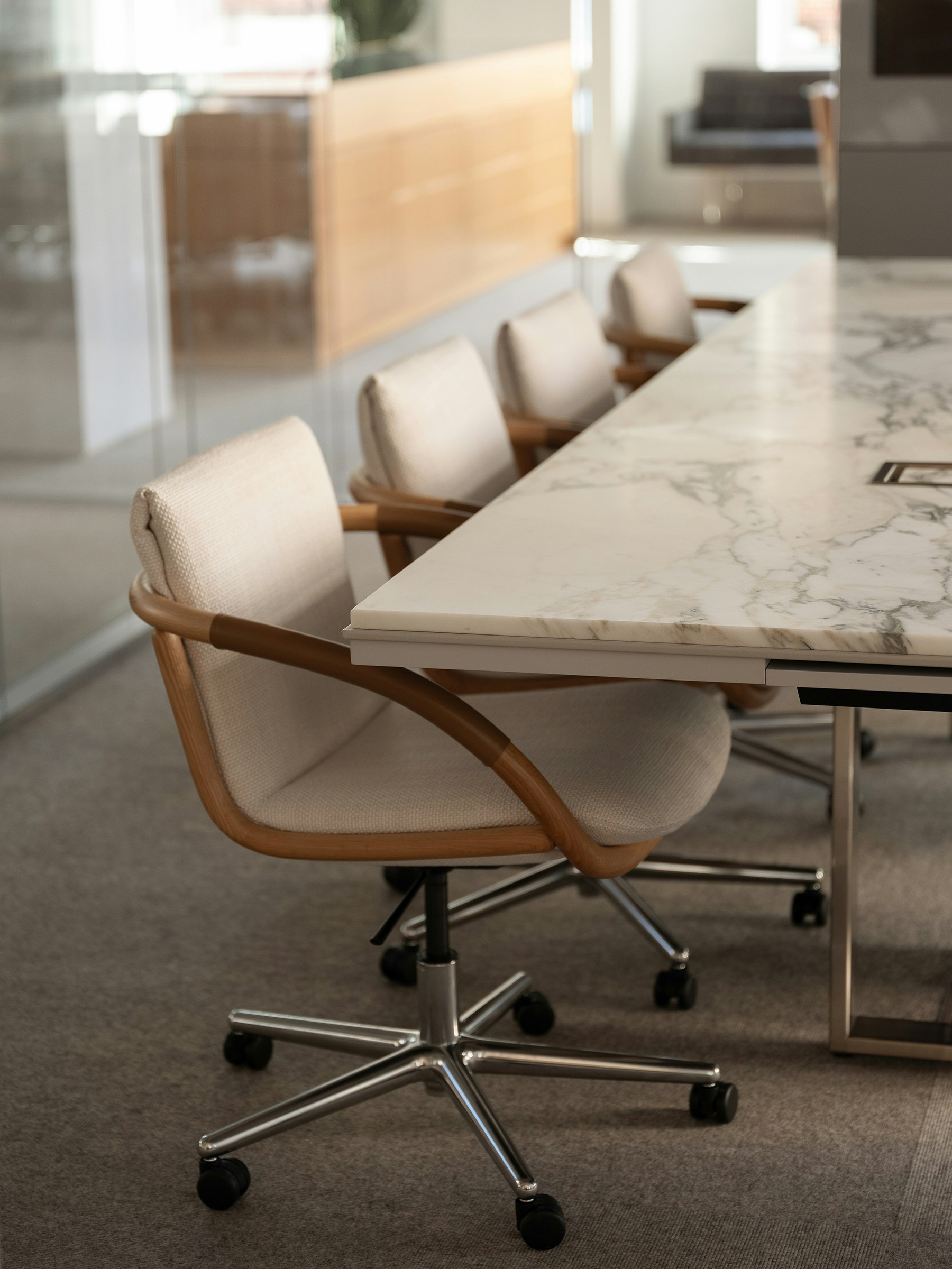 Four Full Loop Chairs designed by EOOS with an Oak frame upholstered with Capri in Snow, with a Highline Conference Table with an Arabescato Corchia marble top, viewed at an angle.