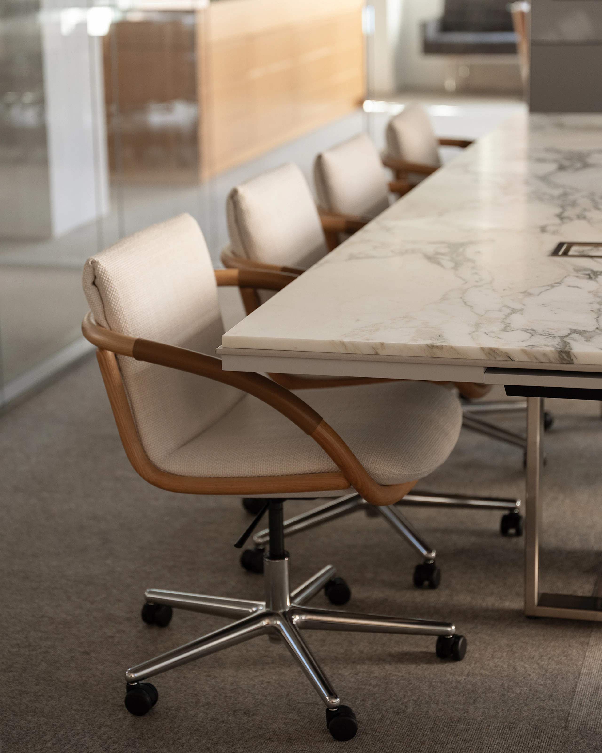 Four Full Loop Chairs designed by EOOS with an Oak frame upholstered with Capri in Snow, with a Highline Conference Table with an Arabescato Corchia marble top, viewed at an angle.