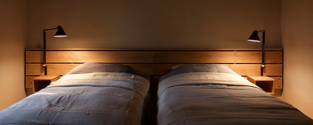 Two NJP Wall Lamps on a bed headboard in a bedroom setting