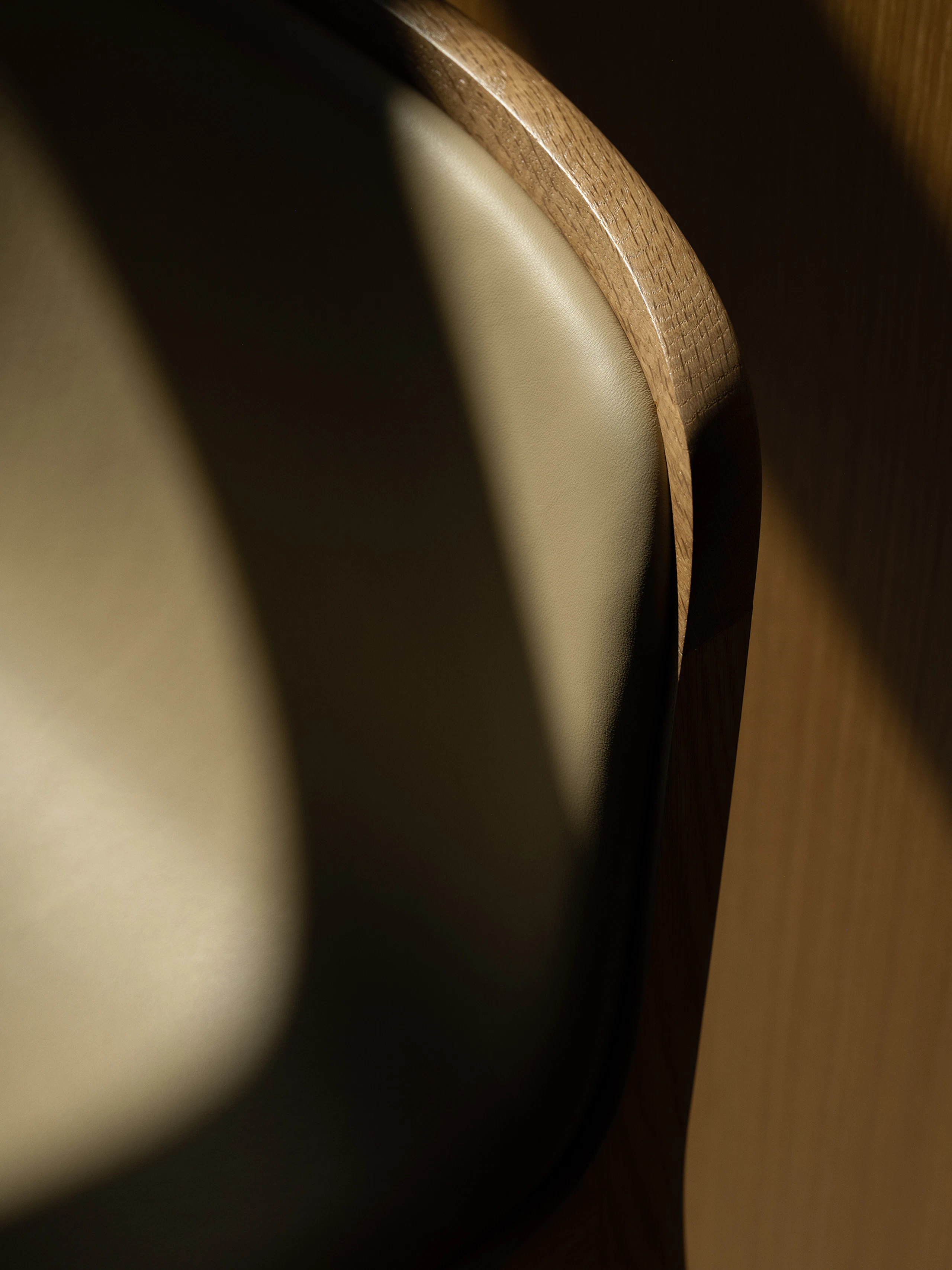 Detail shot of a counter height Lijn Stool seatback in Natural Oak, fully upholstered with Bristol Leather in Champagne, viewed from above at an angle.