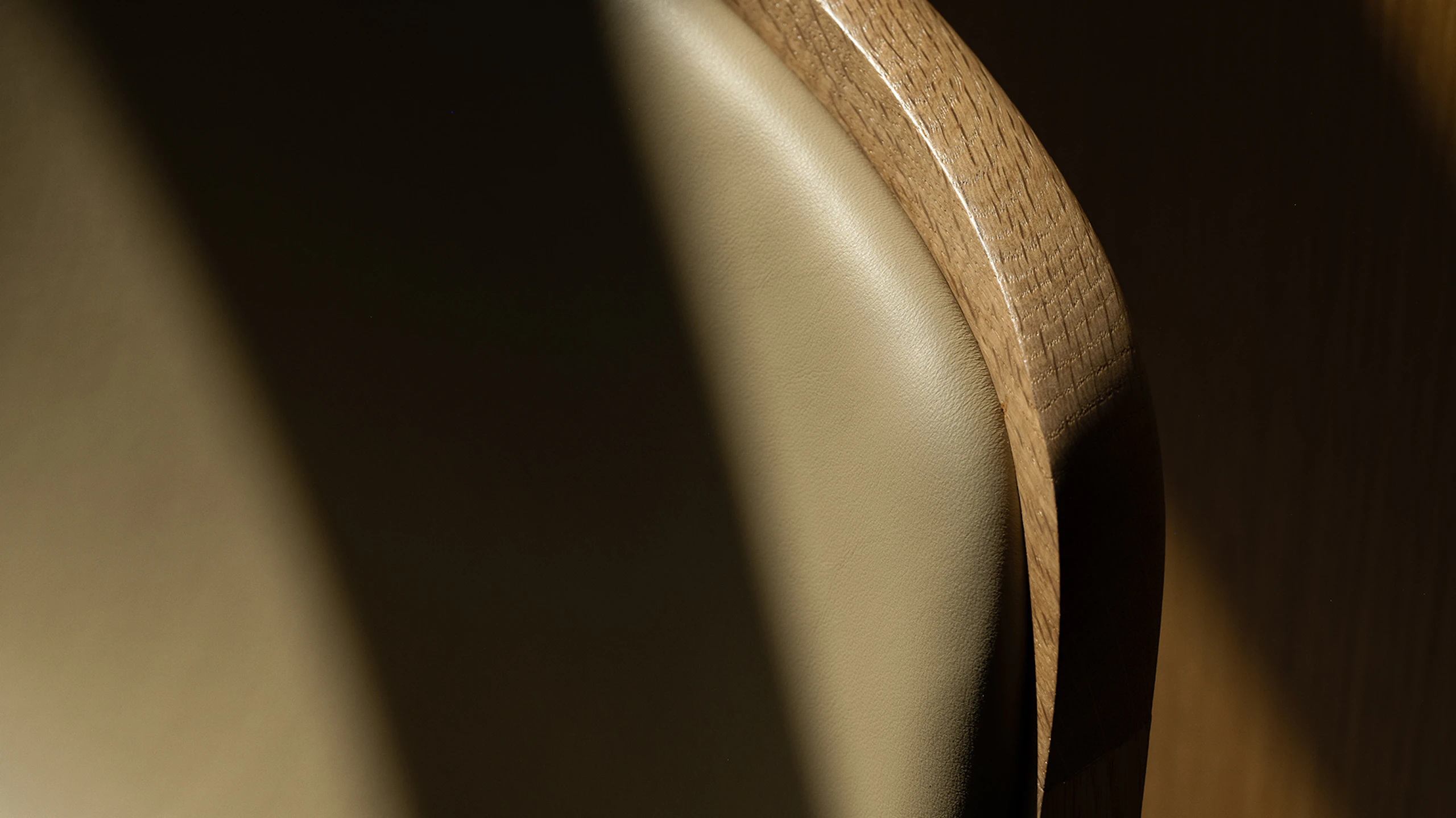 Detail view of a Lijn Stool backrest in Natural Oak fully upholstered with Bristol leather in Champagne, viewed from above.