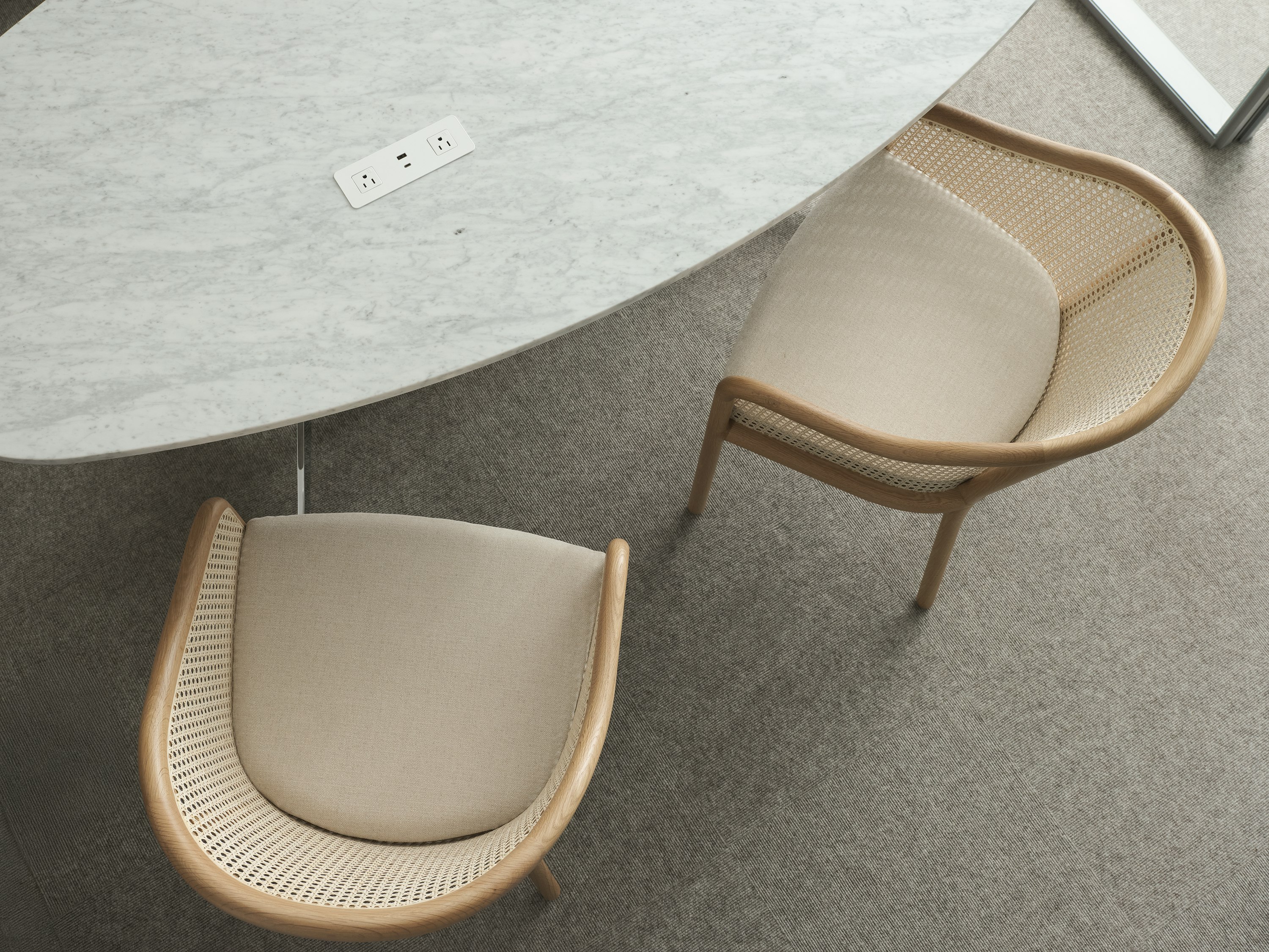 MP Height Adjustable Table with tabletop power in White Carrara Marble with two cane-back Landmark Chairs upholstered with Petra in Dreamy, viewed from above.