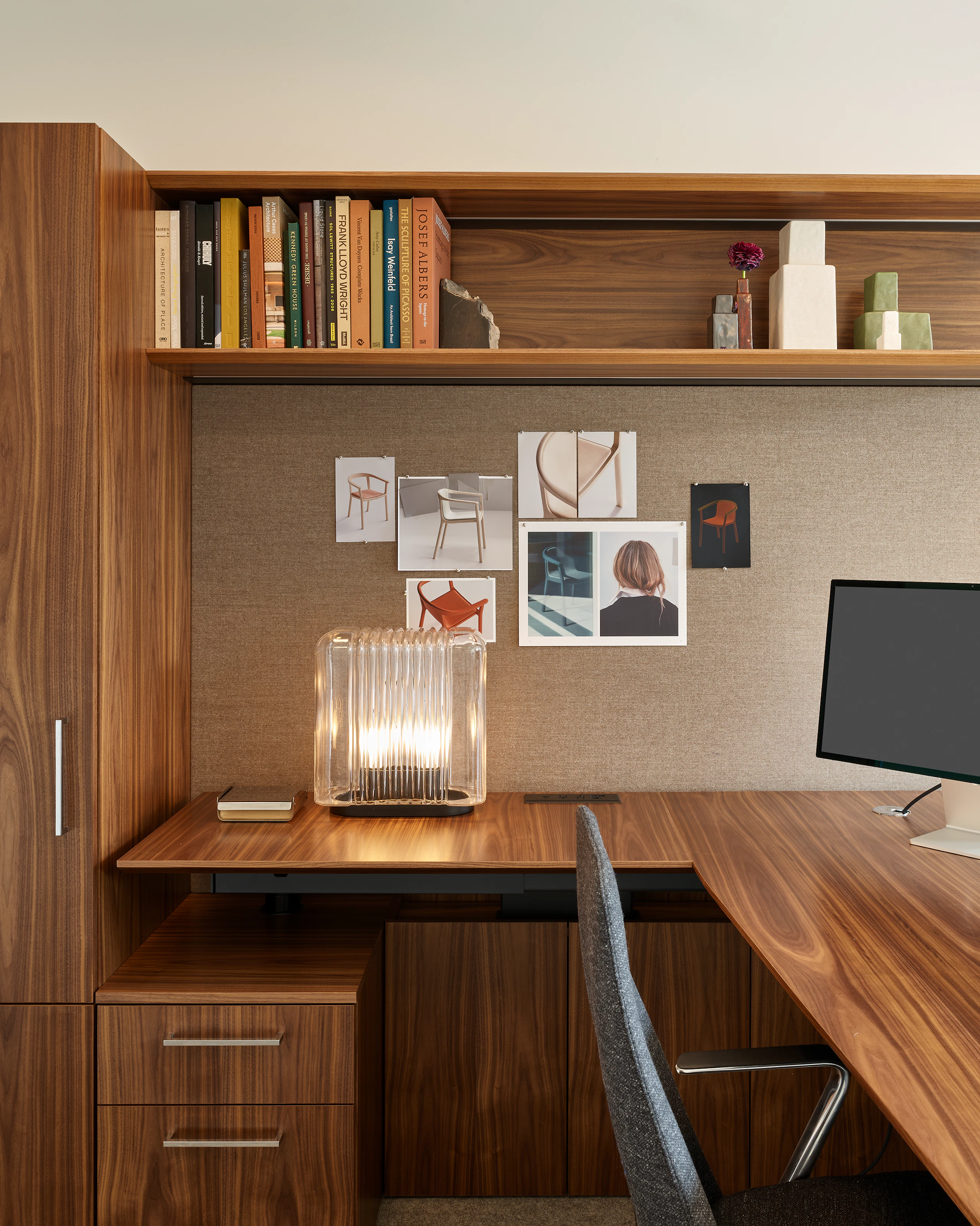 Geiger One Casegoods in Natural Flat Cut Walnut with a Geiger Taper Chair by Mark Goetz viewed from the side with office accessories including a table lamp and books in overhead storage, in a private office in the Geiger DatesWeiser Chicago Showroom