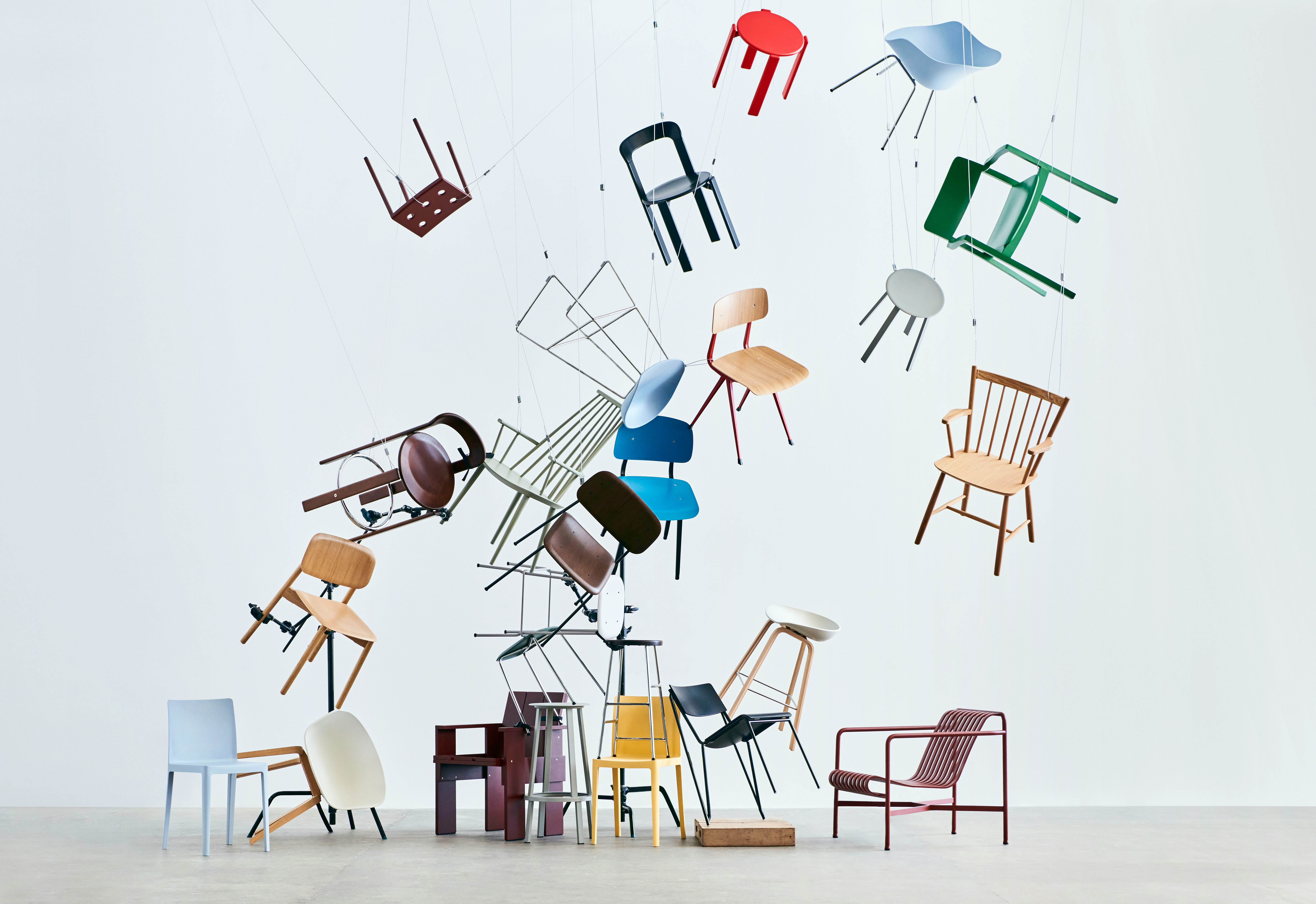 A colorful variety of HAY seating suspended from the ceiling and arranged in a way that they appear to be falling.