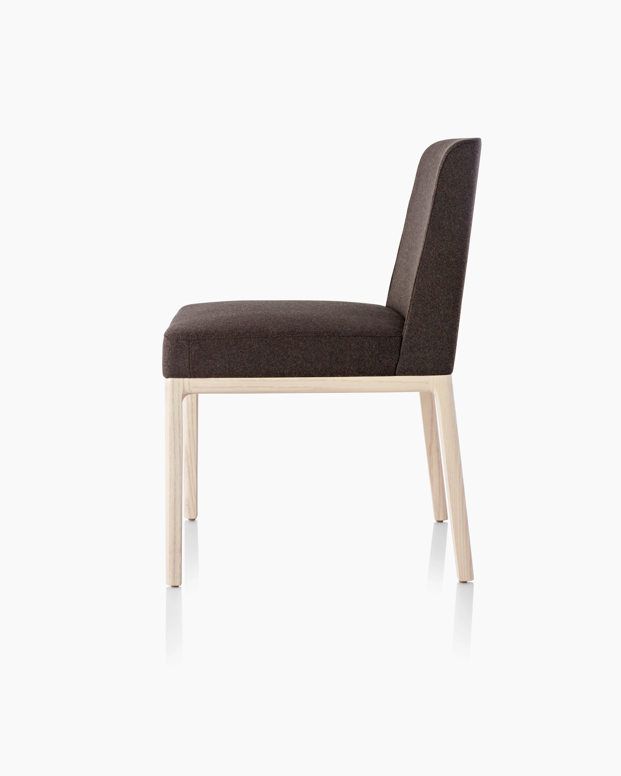 Side view of an armless Nessel side chair with black fabric upholstery and a wood frame with a light finish.