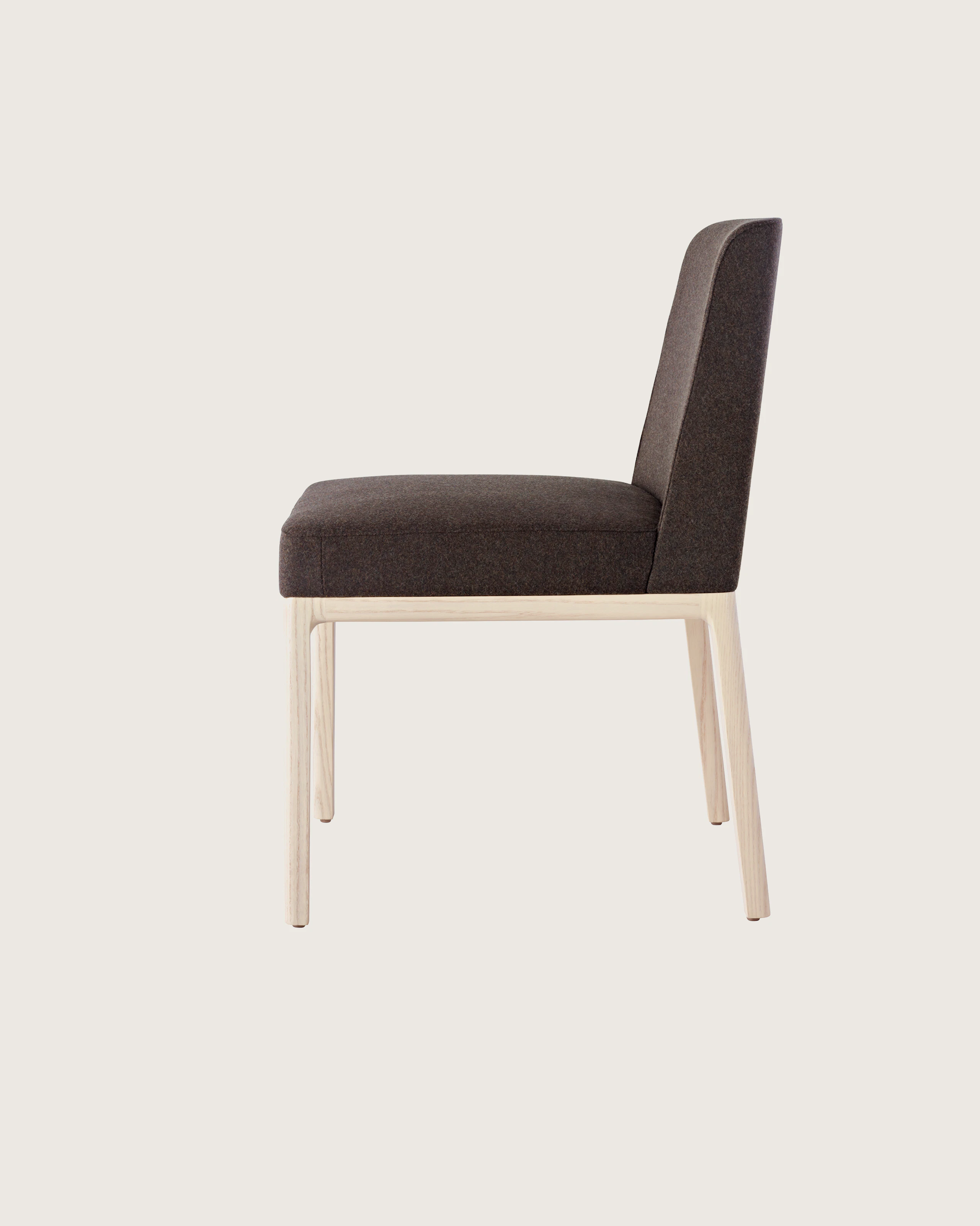 Side view of an armless Nessel side chair with black fabric upholstery and a wood frame with a light finish.