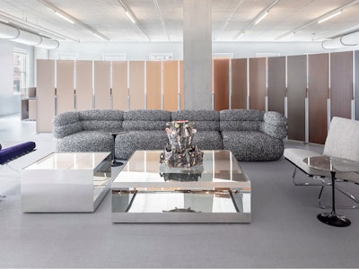 The Knoll showroom at MillerKnoll Design Days furnished with two purple velvet Knoll Barcelona Chairs, a tuxedo Biboni Sofa, and two large glass coffee tables