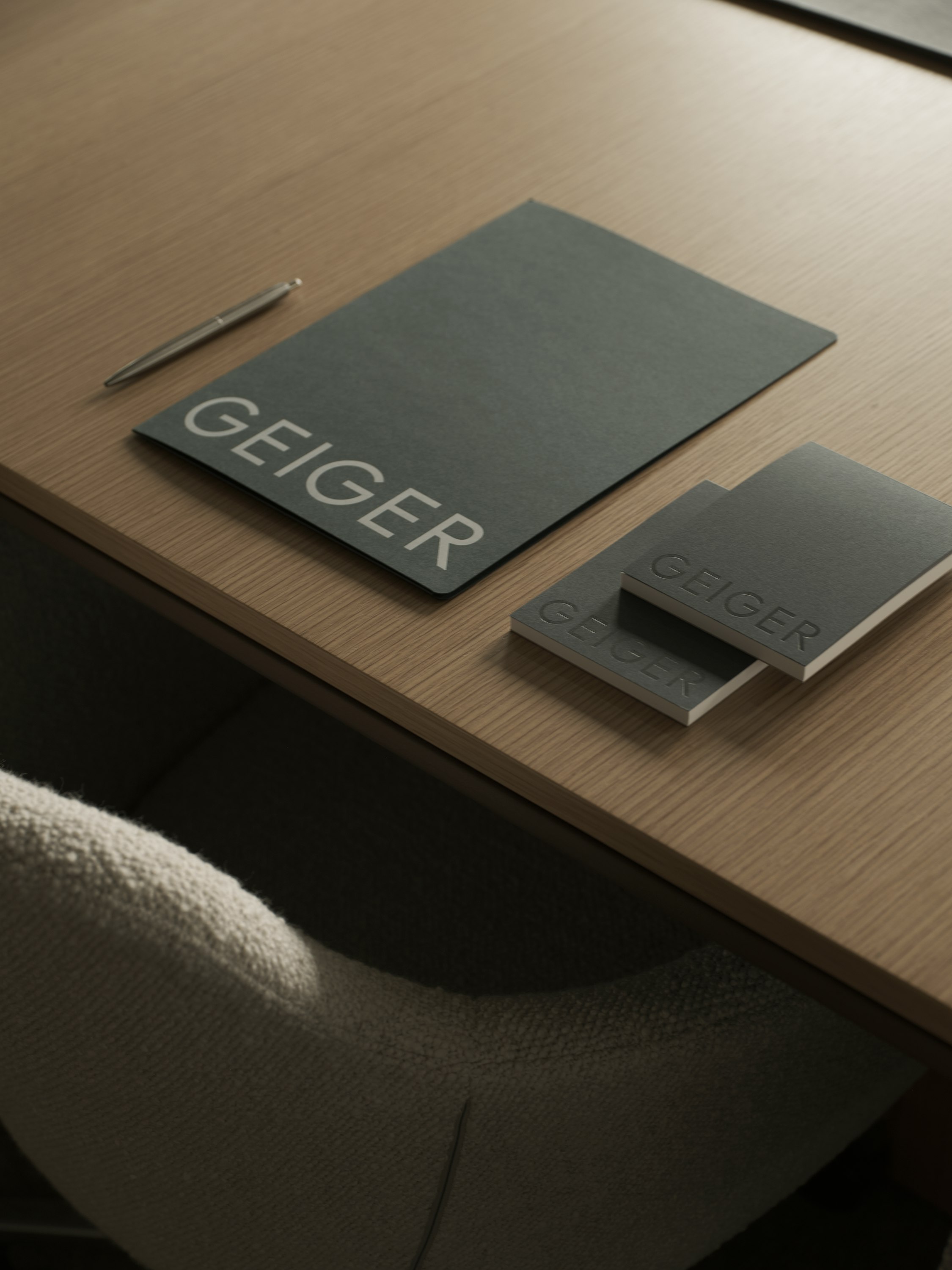 Ascent Conference Table in Natural Rift Cut Oak styled with various Geiger amenities, with a Saiba Chair upholstered with Pristina in Dove, viewed from above at an angle.