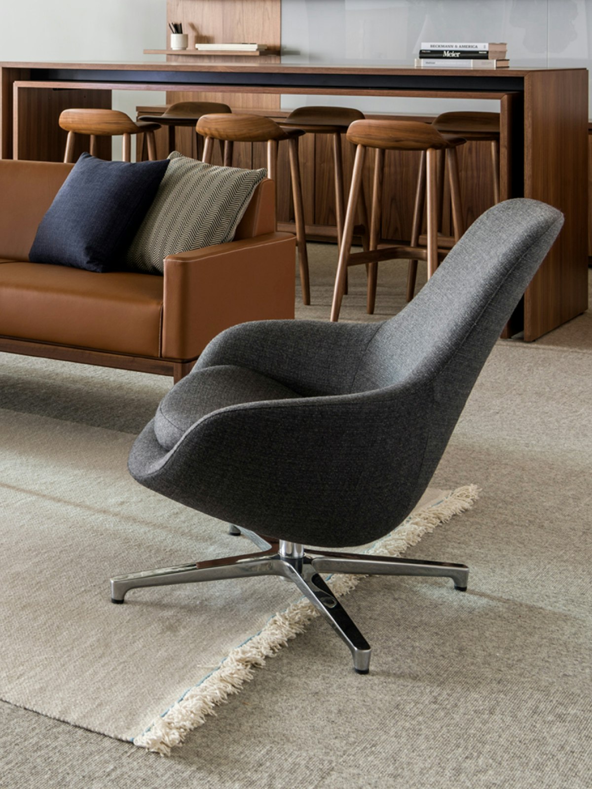 An open office space featuring a sitting area that includes a Saiba Lounge Chair; sofa; and stools.