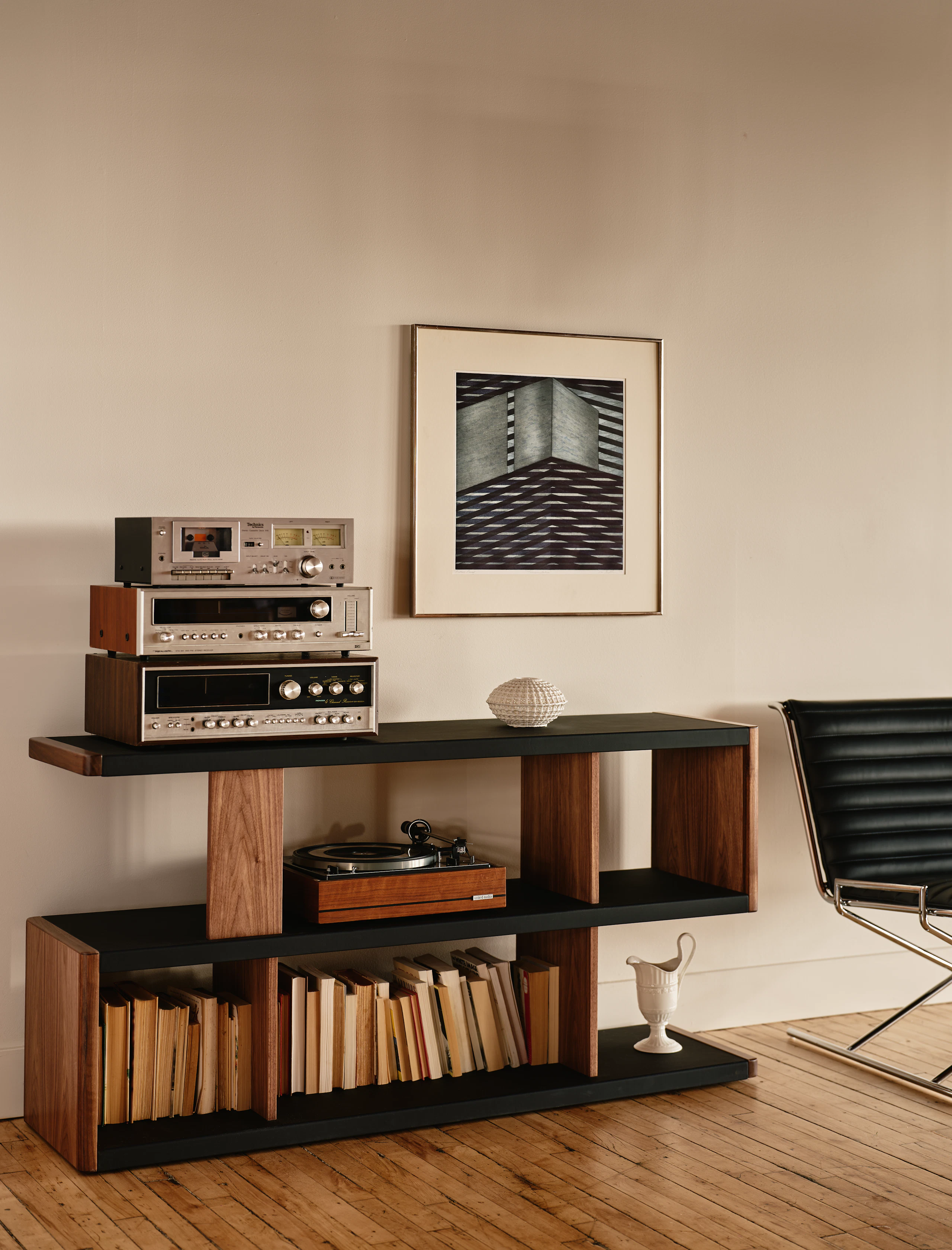 New Canaan Low Bookshelf designed by BassamFellows for Geiger in Walnut with Black Leather shown angled in a residential setting with books and objects on shelves.