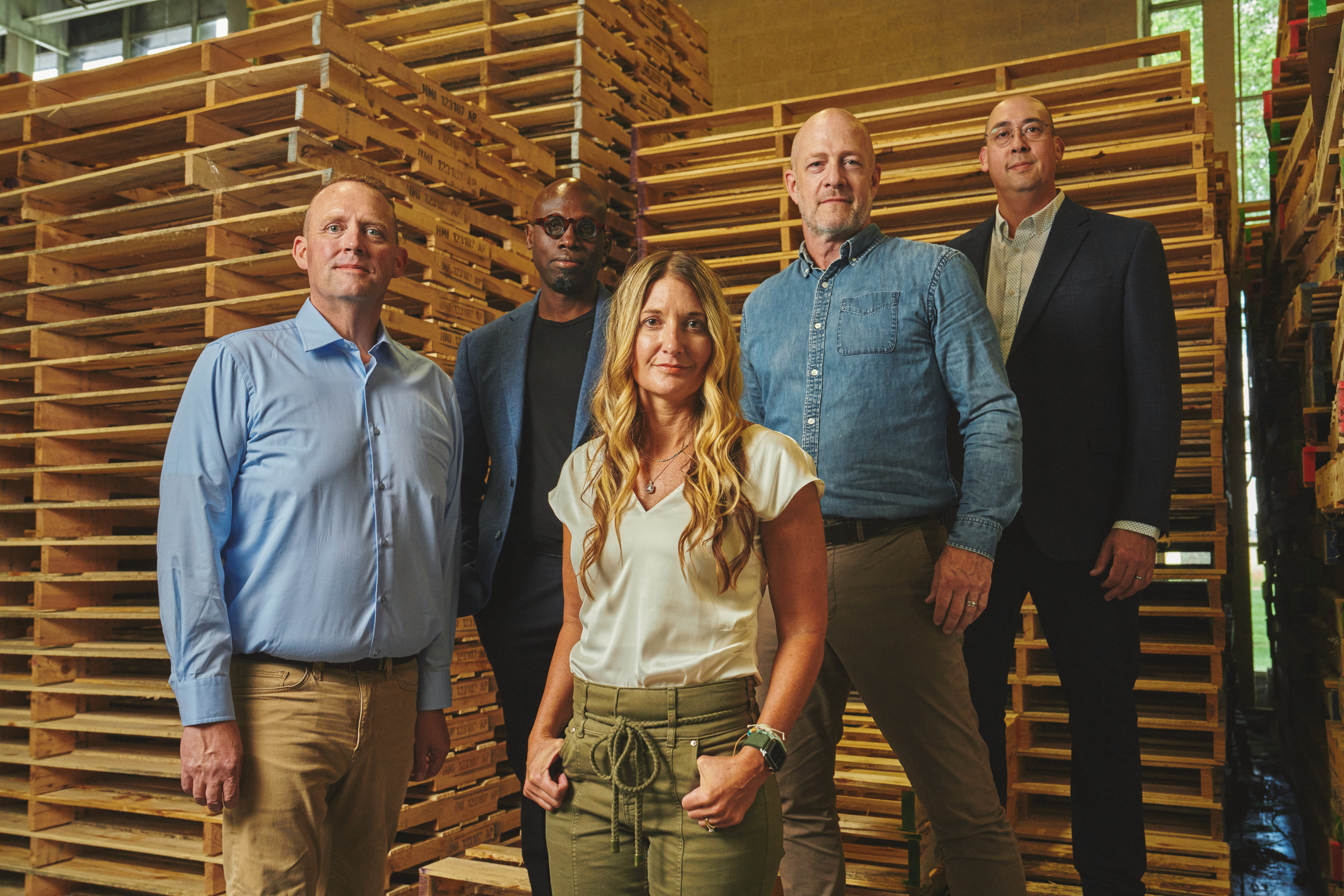 The members of Team Carbon posing in front of stacks of wooden pallets.