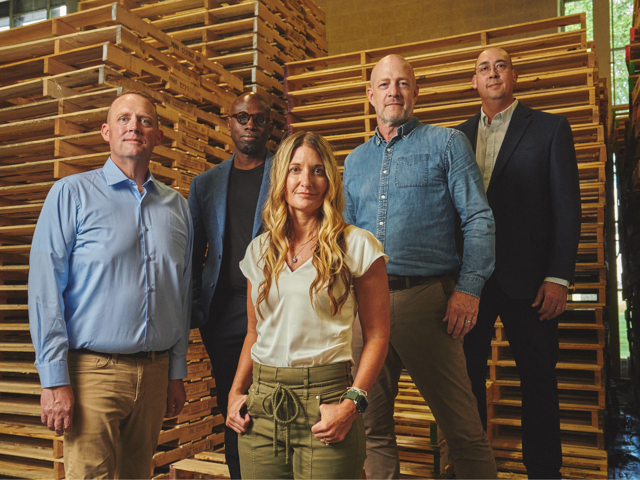 The members of Team Carbon posing in front of stacks of wooden pallets.