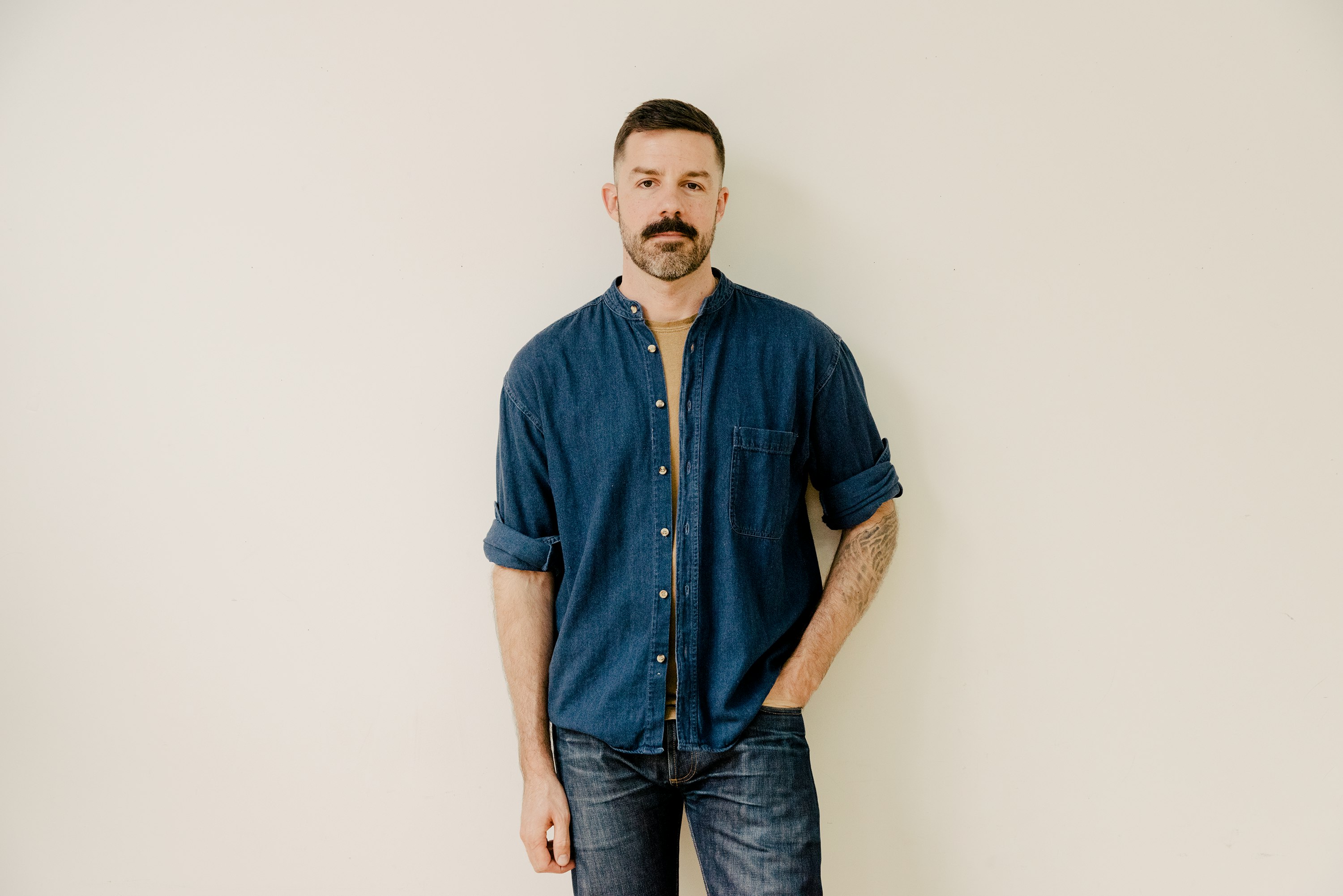 Textile designer Joseph White posing in front of a wall.