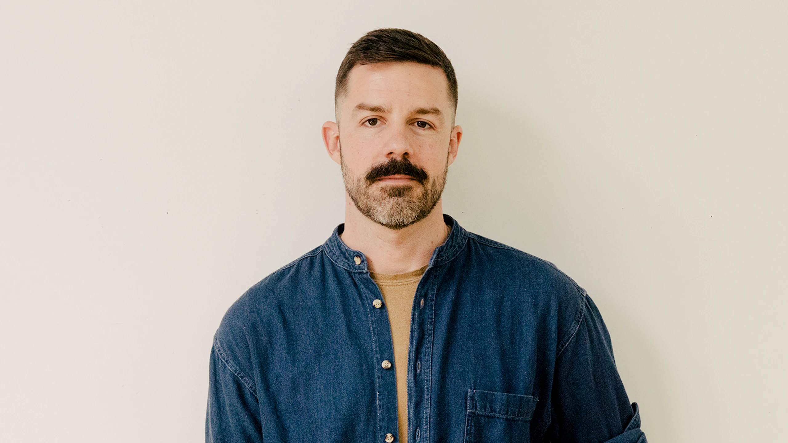 Textile designer Joseph White posing in front of a wall.