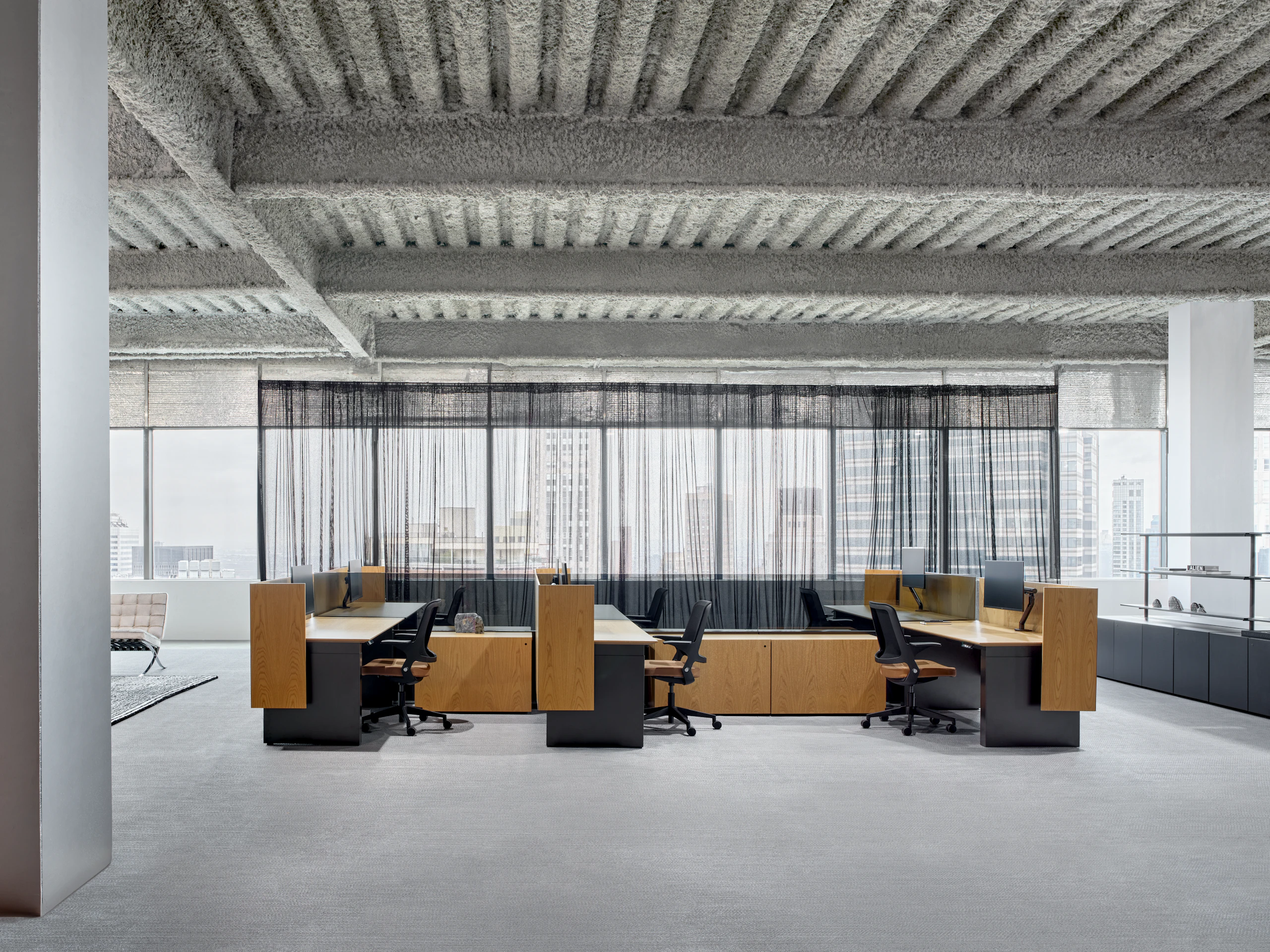 A six pack of workstations is in an open office setting, along with shared storage credenzas and open shelving to the side of the work stations.
