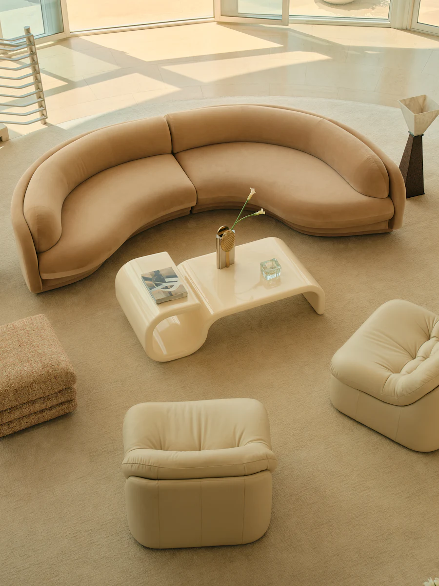 Living room with curved sofa set: large curved sofa, round ottomans, and white coffee table