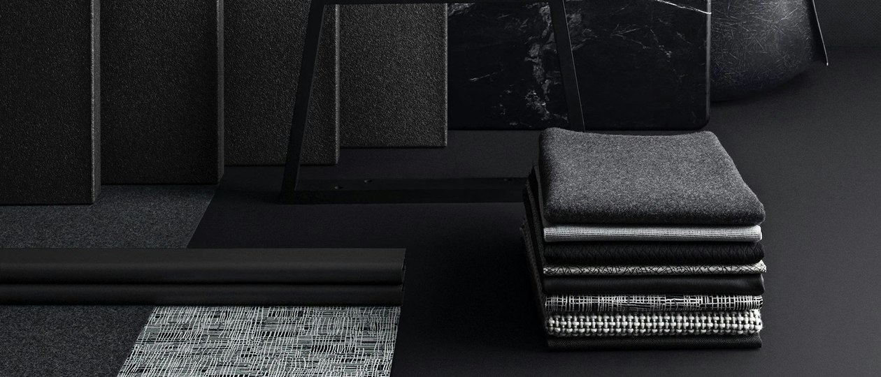 A stack of folded textile material placed neatly on the floor next to hard-finish materials.