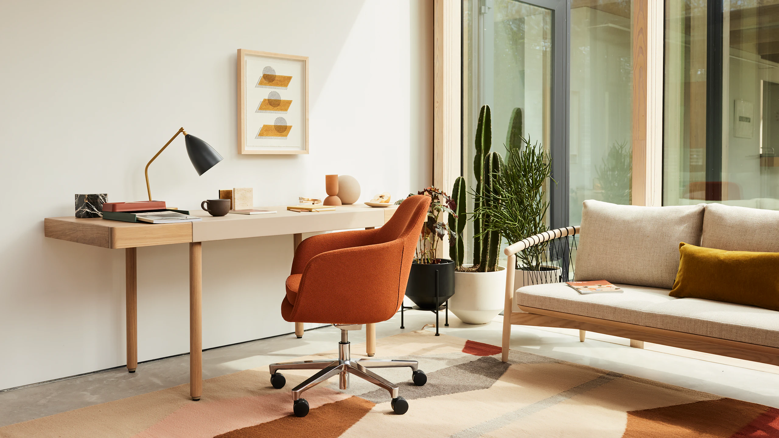 A home office setting with the New Canaan Leatherwrap Sit-to-Stand Desk, Saiba office chair and Crosshatch Settee.