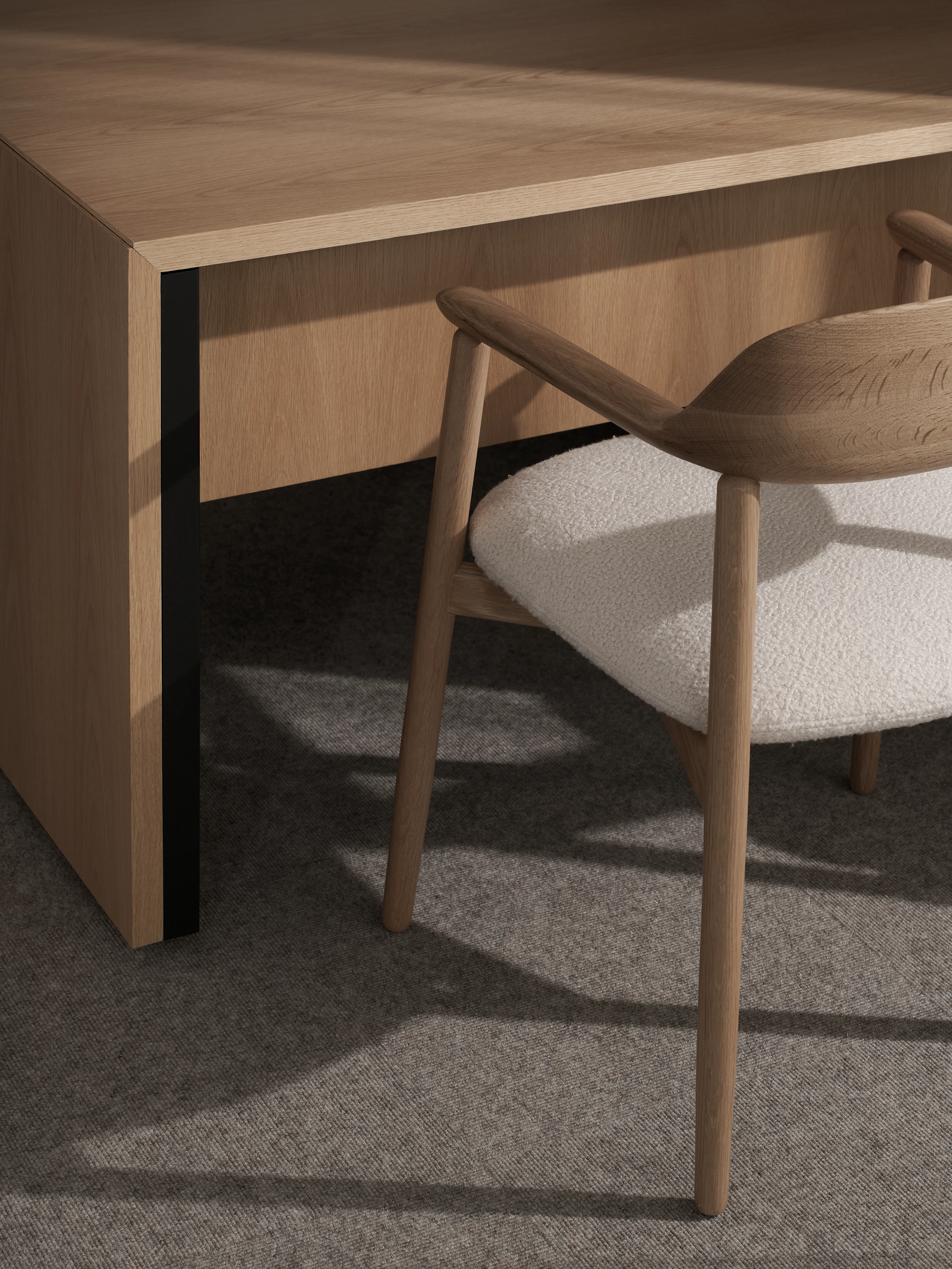 Detail view of a Geiger One Private Office cascade leg in Natural Flat Cut Oak with a Crosshatch Armchair in Natural Oak upholstered with Maharam Firth in Limewash, viewed at an angle.