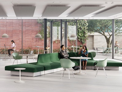 Modern lounge area with green modular sofa, light wood tables, and various seating options. Large windows overlook a green space with trees.