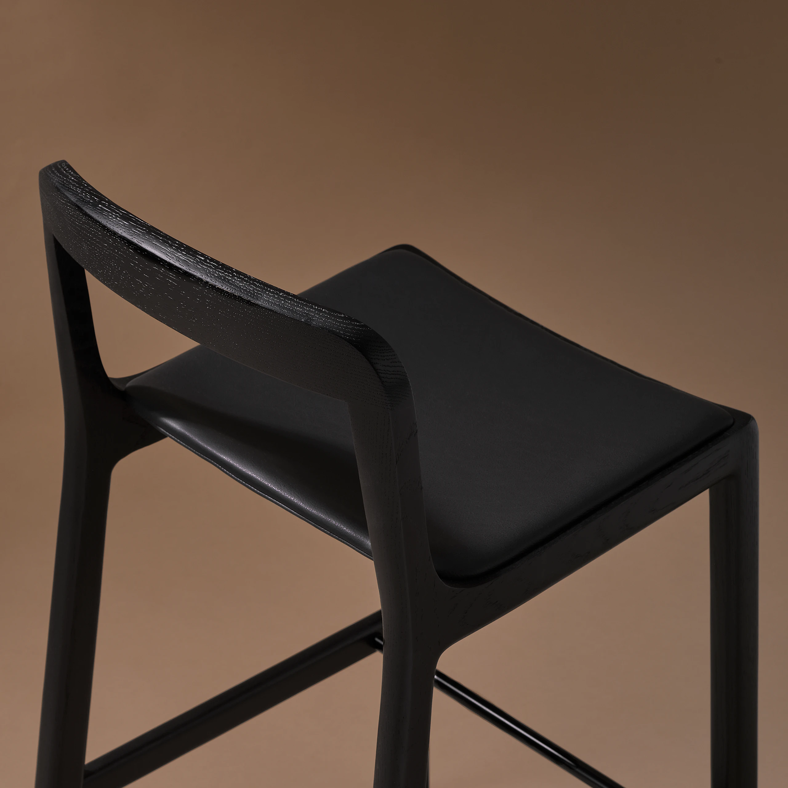 Lijn Stool by Carole Baijings for Geiger in Ebonized Oak frame upholstered with Maharam Prone Leather in Obsidian, detail shot on a neutral background.
