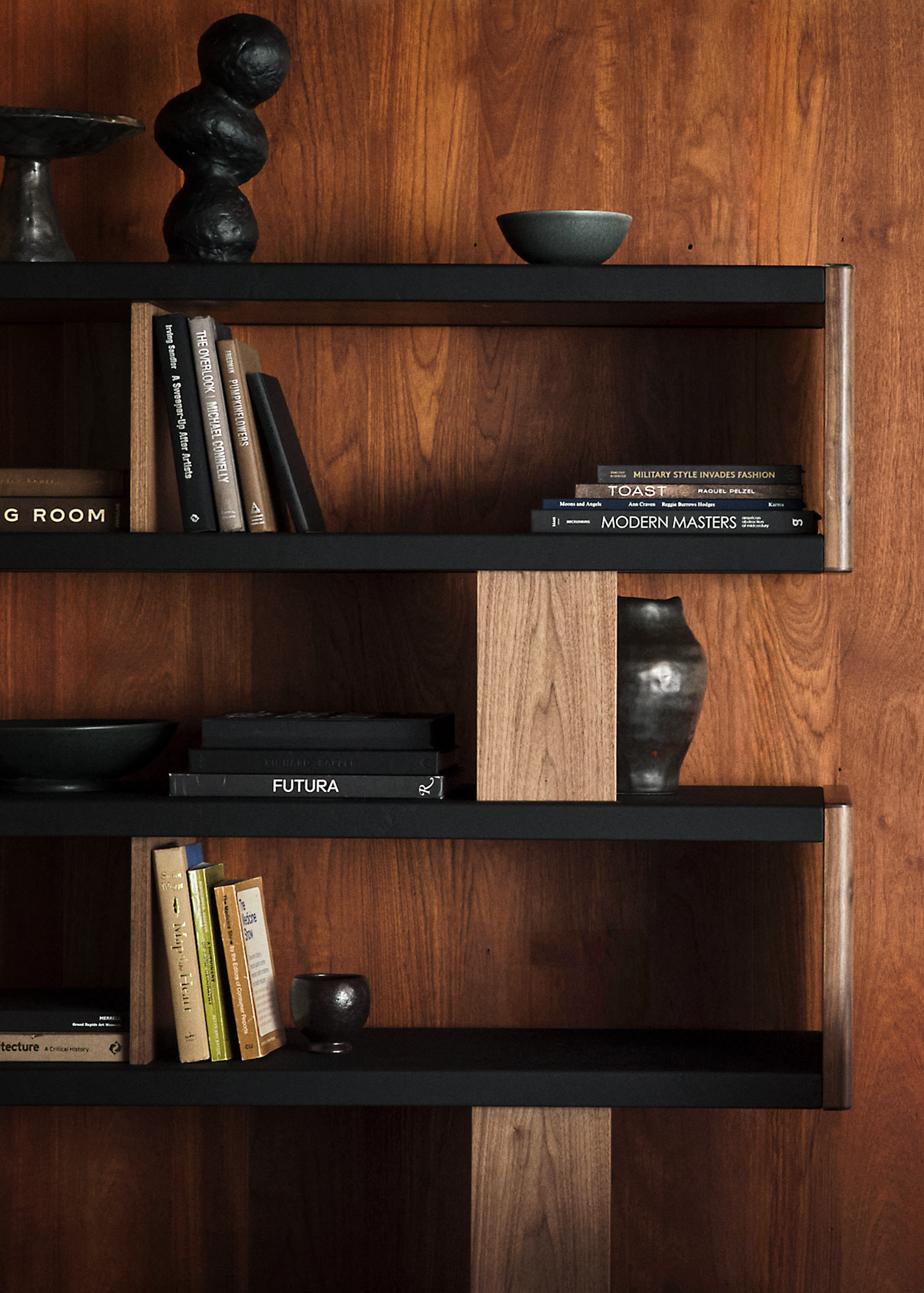 New Canaan Bookshelf designed by BassamFellows for Geiger in natural walnut with black leather shown in a detail shot styled with books and decorative objects.