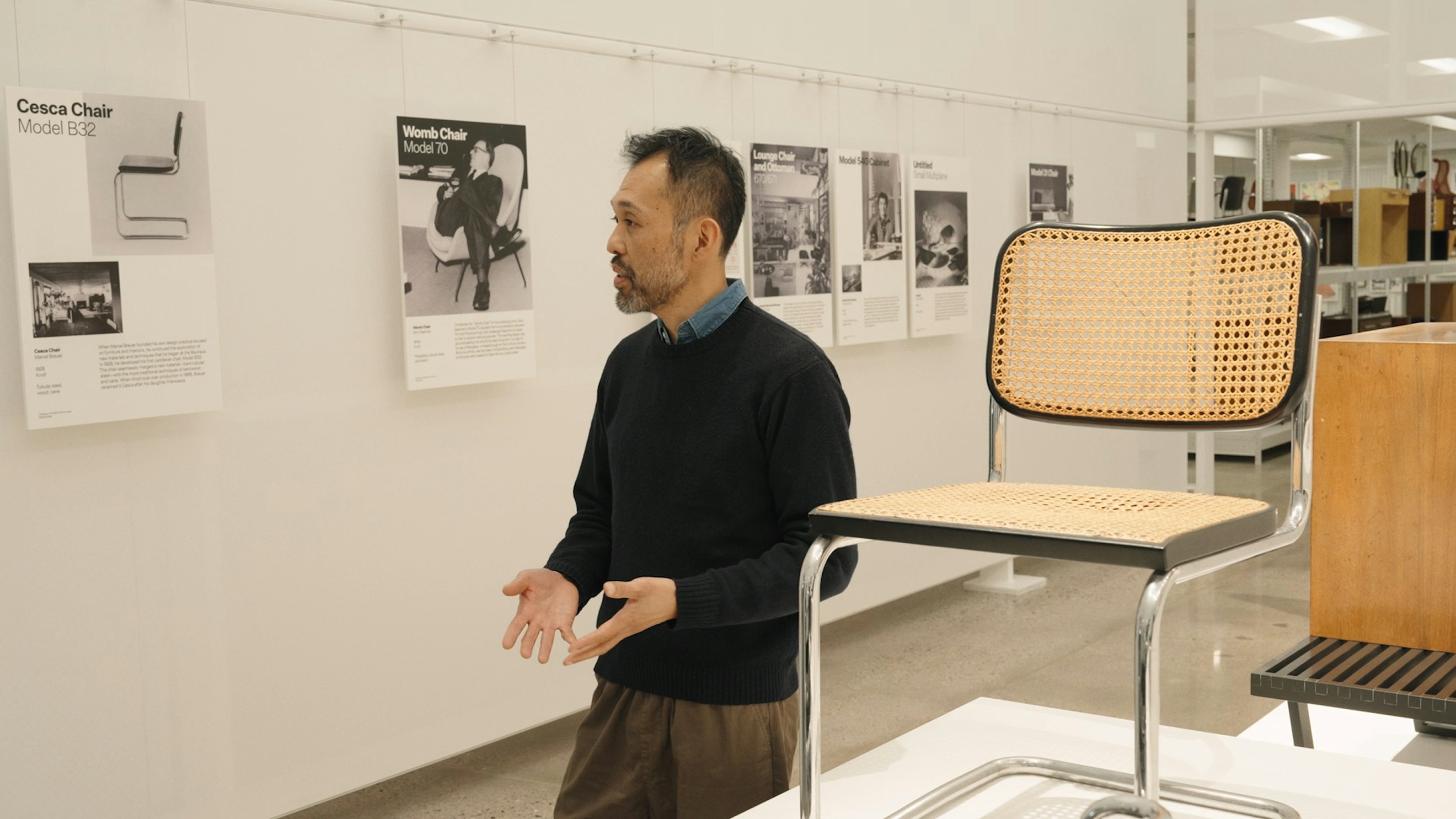 Keiji Takeuchi walking past a Cesca Chair and several informational placards at the MillerKnoll Archives.
