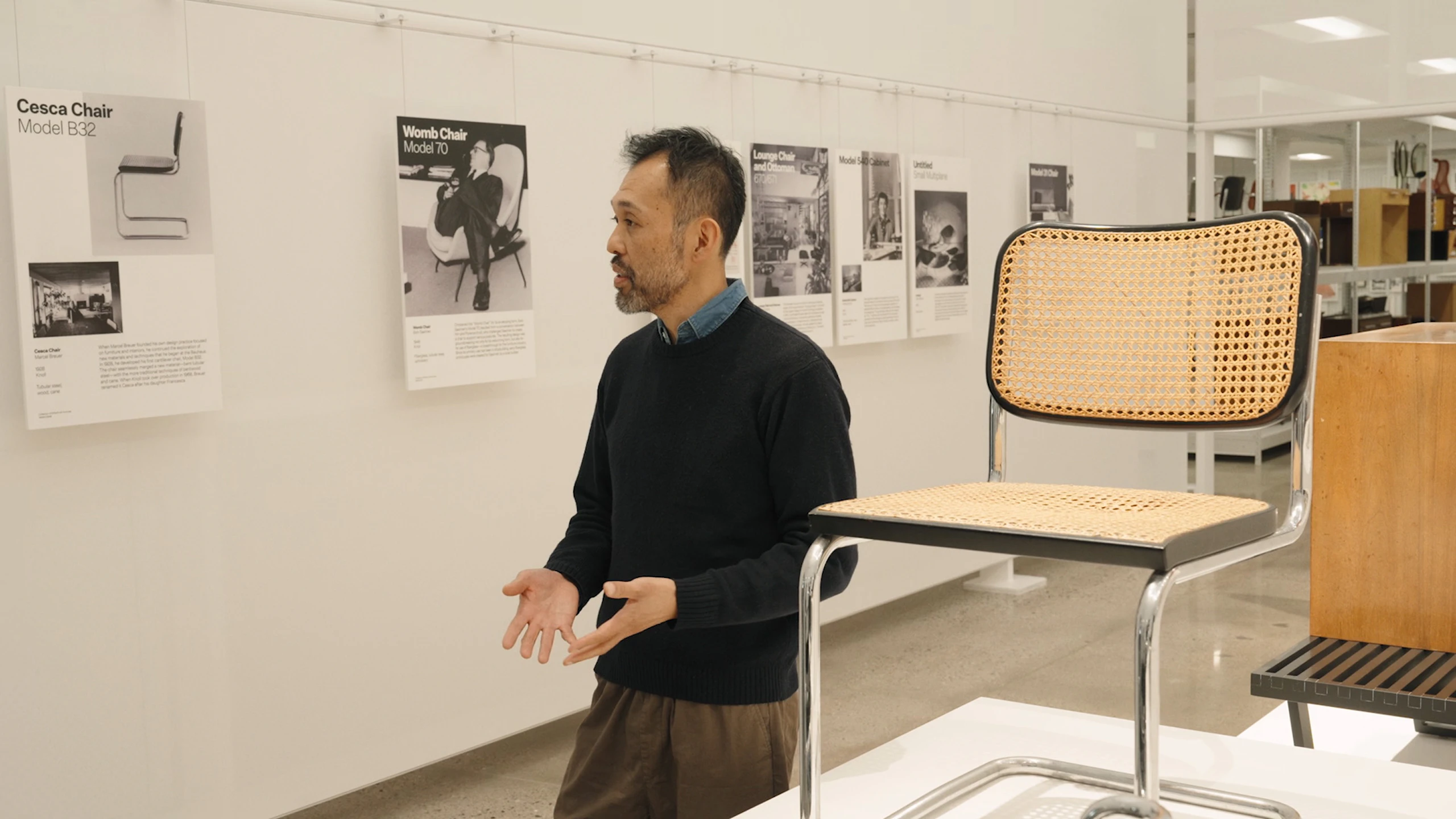 Keiji Takeuchi walking past a Cesca Chair and several informational placards at the MillerKnoll Archives.