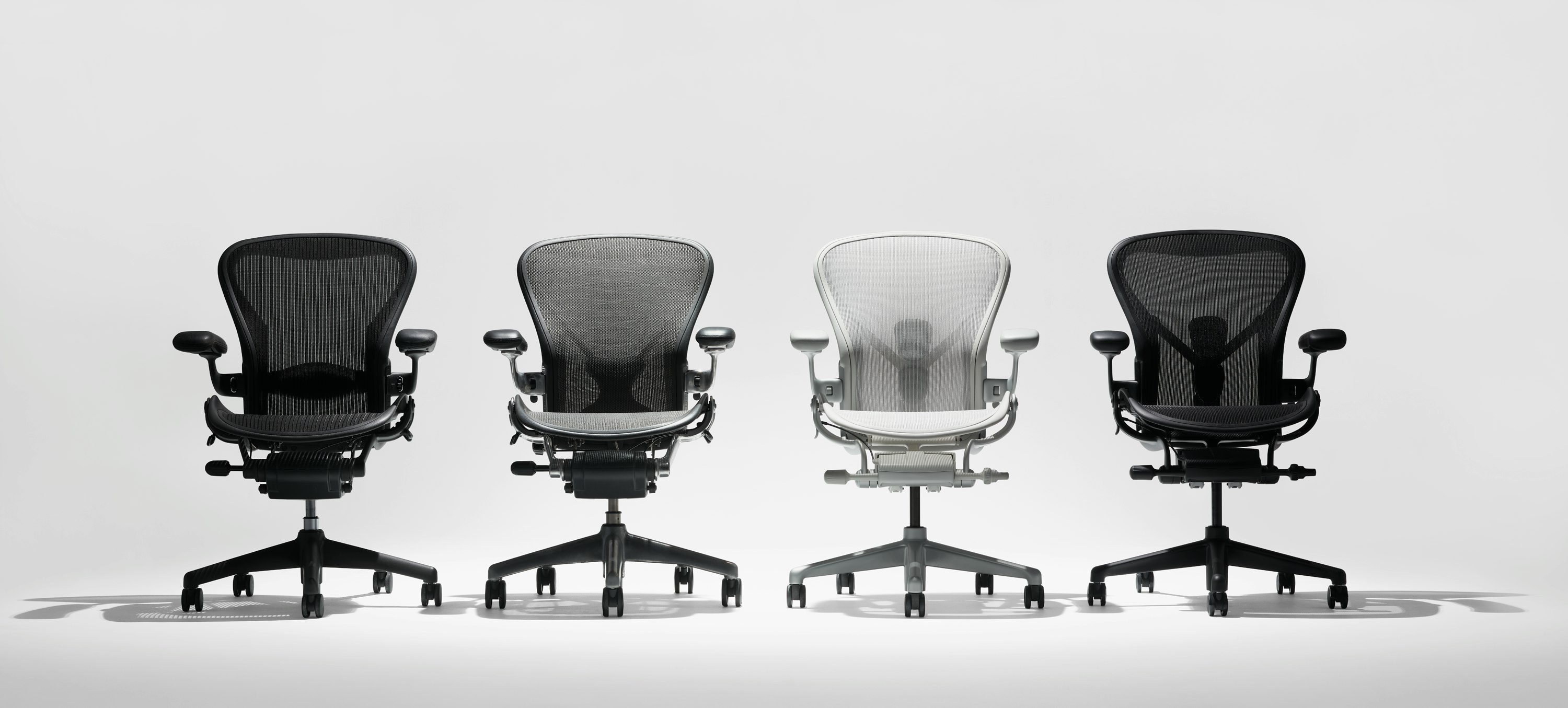 Line up of four Aeron chairs in four colors from light grey to black.
