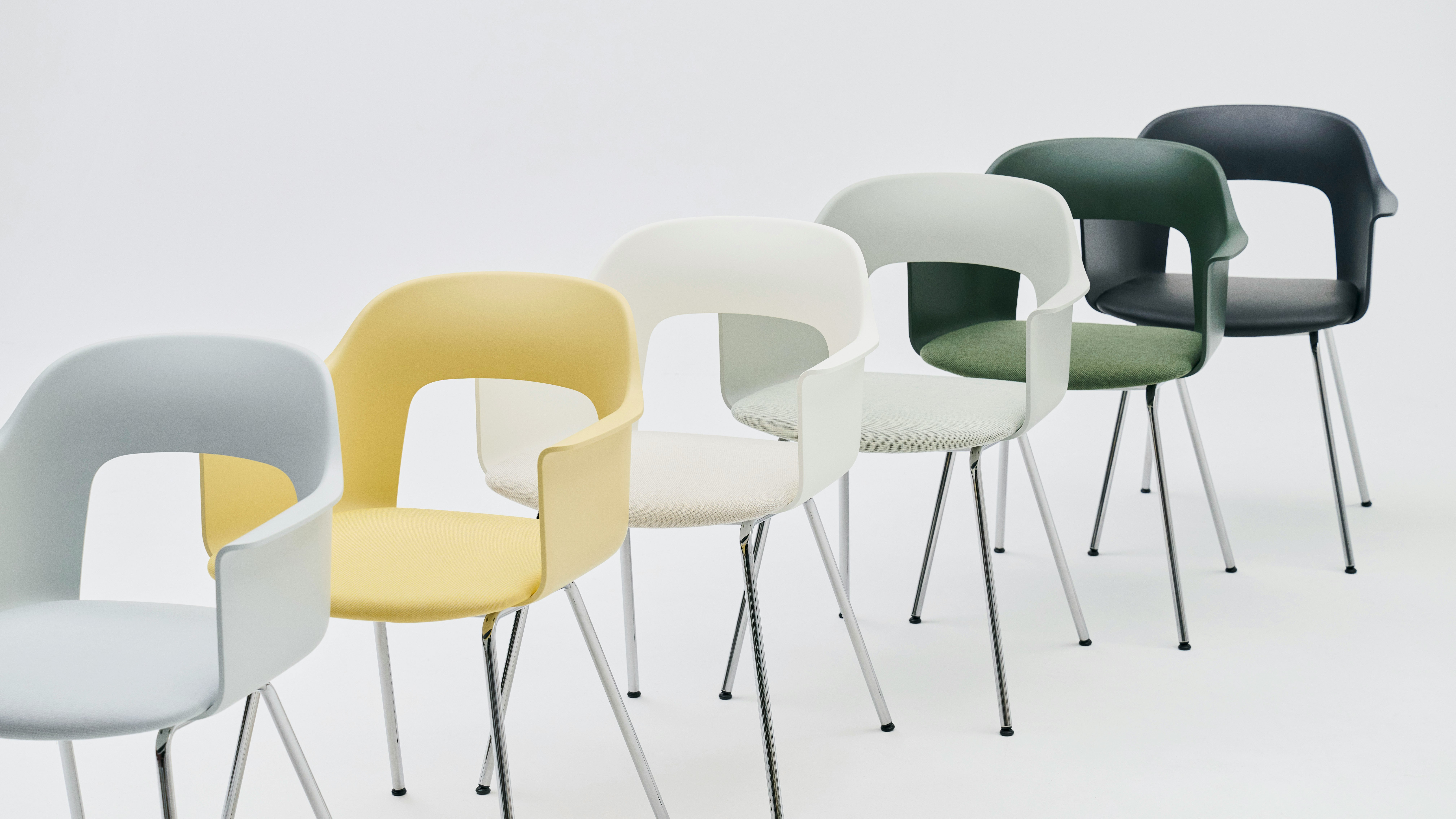 Staggered row of Layout Armchairs 213 and 234 in yellow, green, and dark blue finishes, white background.
